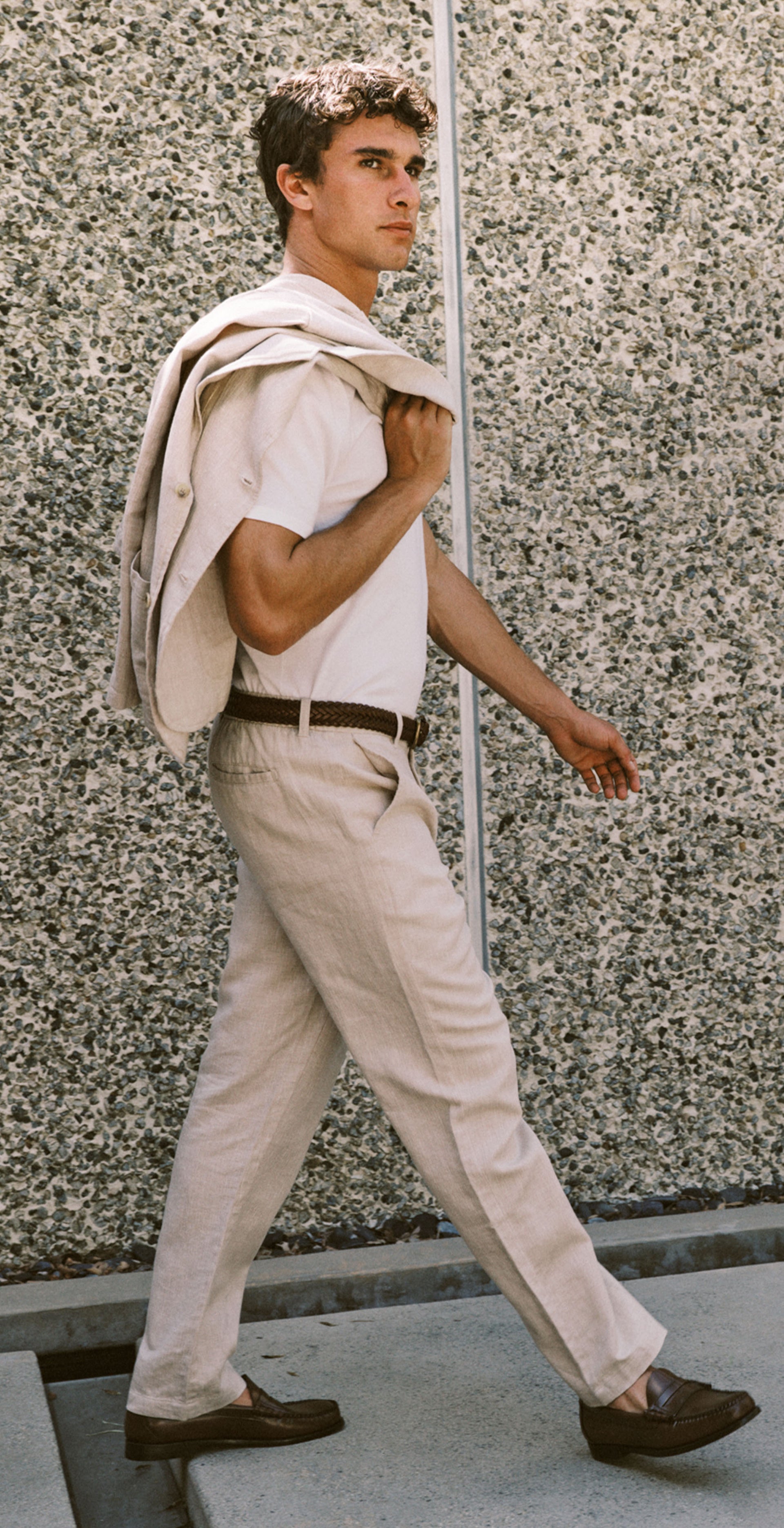 Man wearing a beige suit walking near a pool