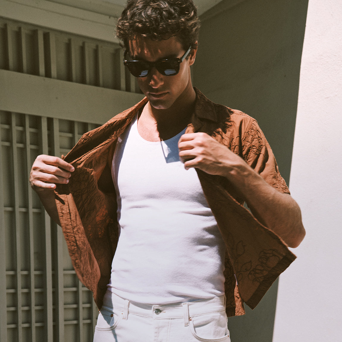 Man wearing a white tank under a brown button down shirt