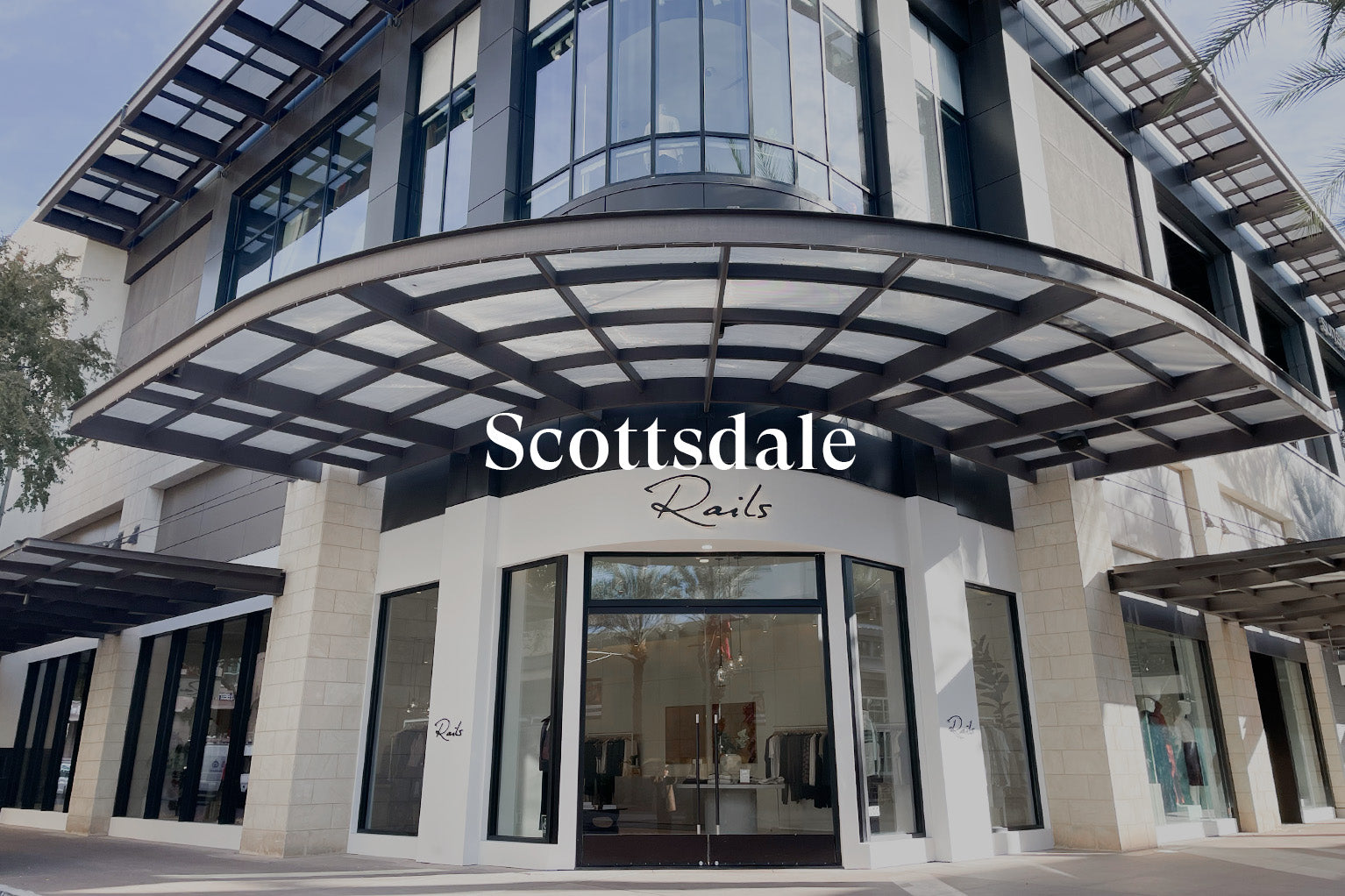 OUTSIDE OF SCOTTSDALE STORE SHOWING THE FRONT ENTRANCE (TWO LARGE GLASS DOORS) WITH RAILS SIGN ABOVE THE ENTRANCE (RAILS IS WRITTEN IN BLACK CURSIVE LETTERS)