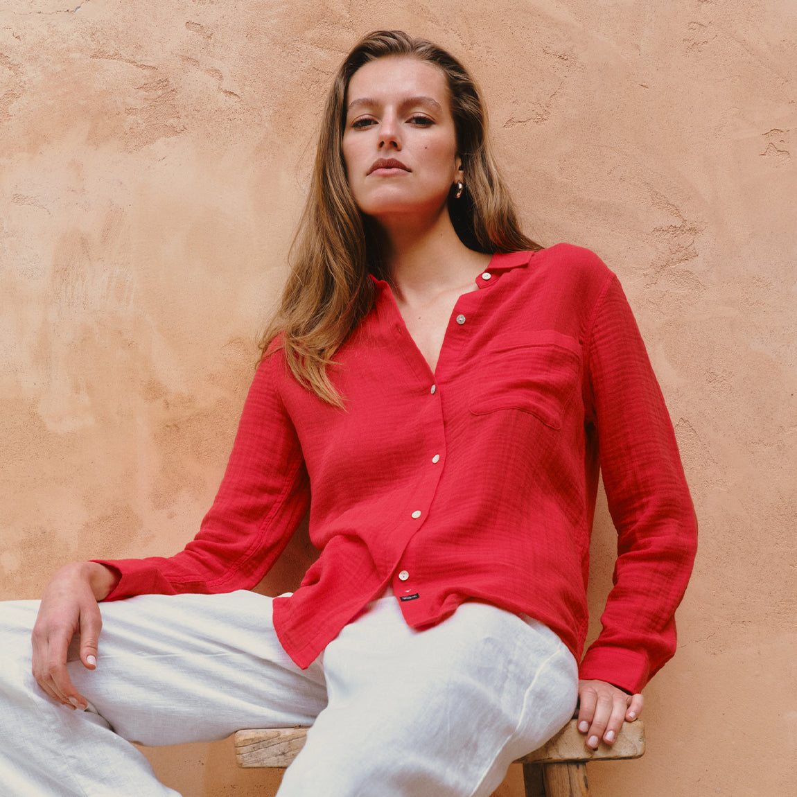 Woman wearing a red button-down shirt with white pants