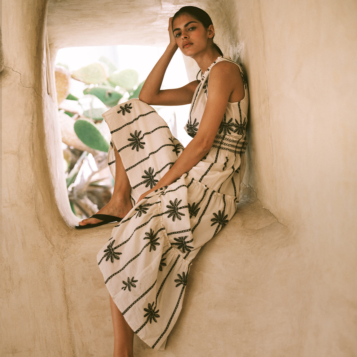 Woman wearing a beige maxi dress with black palm trees 