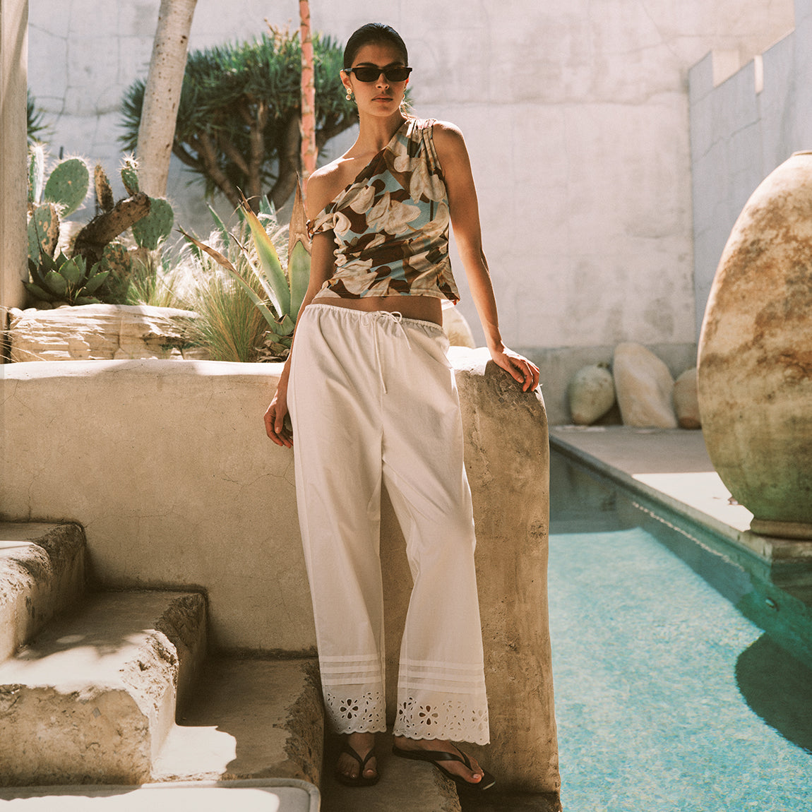 Woman wearing a colorful floral top with white embroidered pants 