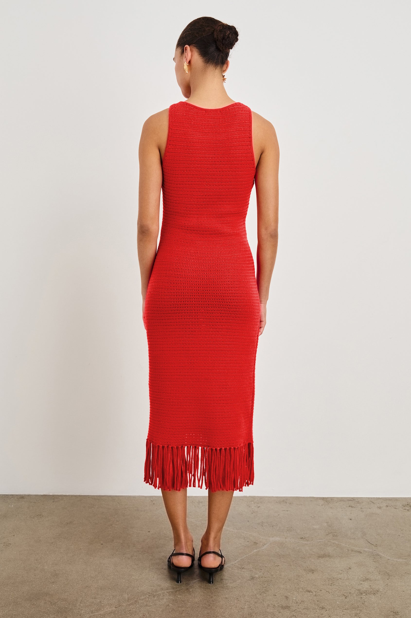 Back view of female model wearing our sleeveless, Nia Midi Dress in color Cherry, featuring crochet structure and fringe details at the hem.