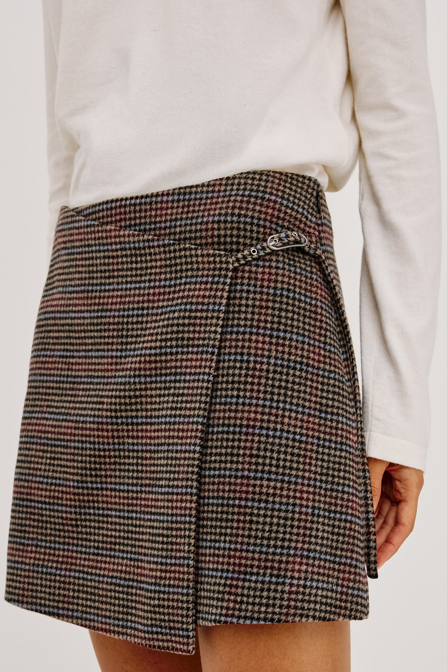 Nial Mini Skirt in Wool Blend With Wrap Front, Buckled Side Strap, Side Welt Pocket, Seam Zip Closure, and Fully Lined in Oxford Plum Colorway - Lower Body Close Up View Featured on Model