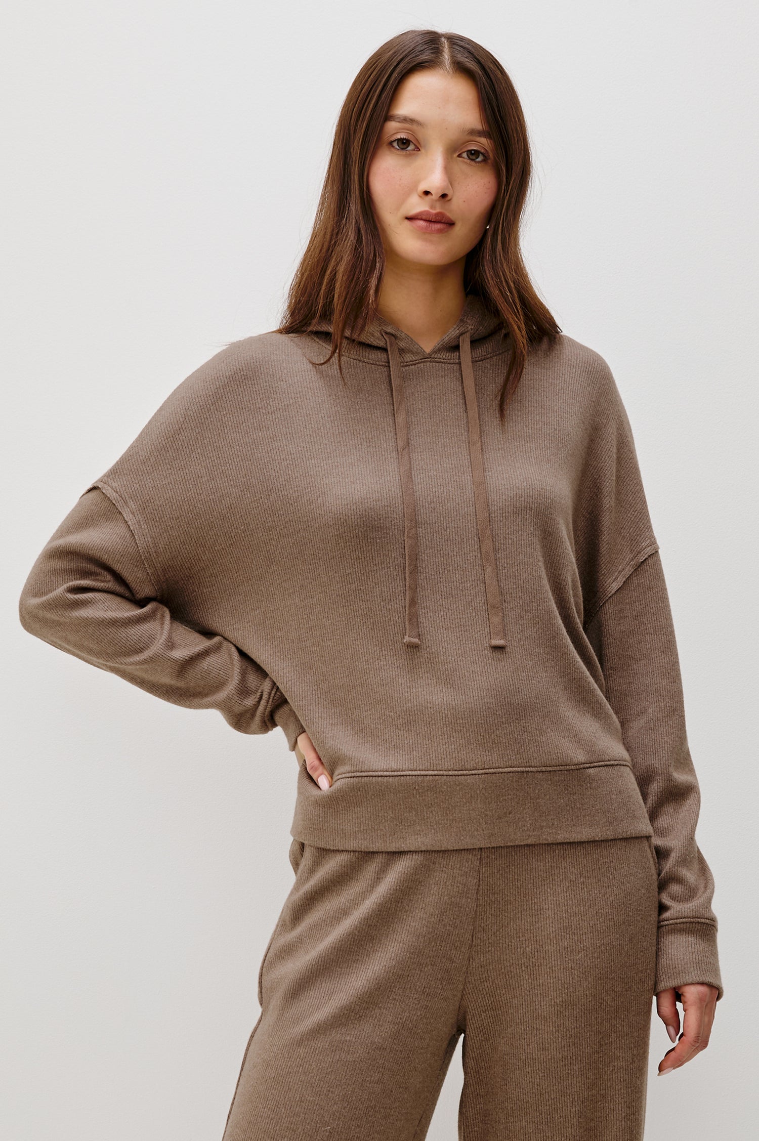 Nico is a hoodie in brushed rib lounge fabrication, with a relaxed fit and drop shoulders in heather latte colorway. Front view featured on model.