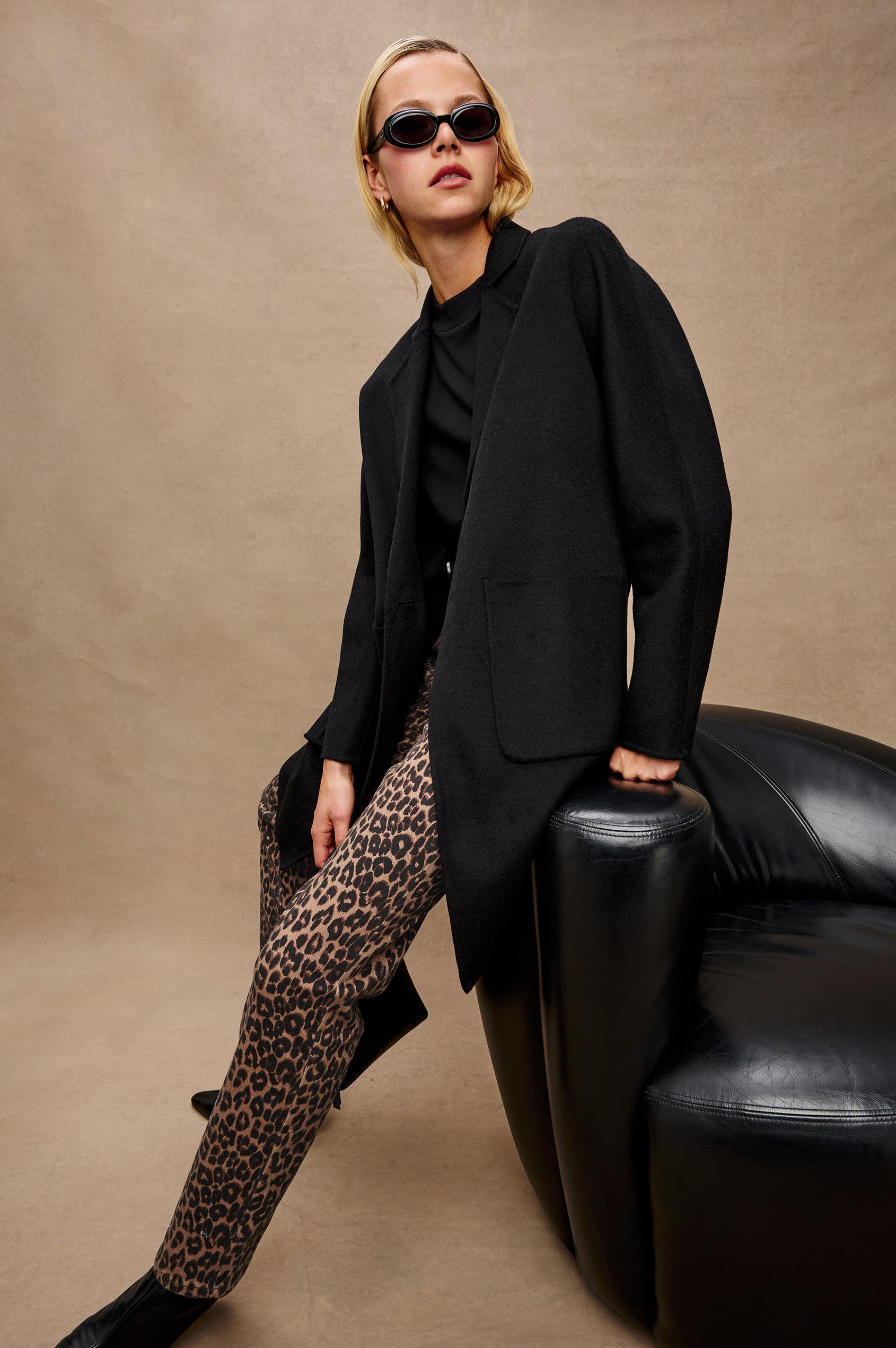 Everest Mid-Thigh Length Coat with Single Button Closure, Notched Lapels and Front Patch Pockets in Black Colorway - Stylized Front Full Body View Featured on Model