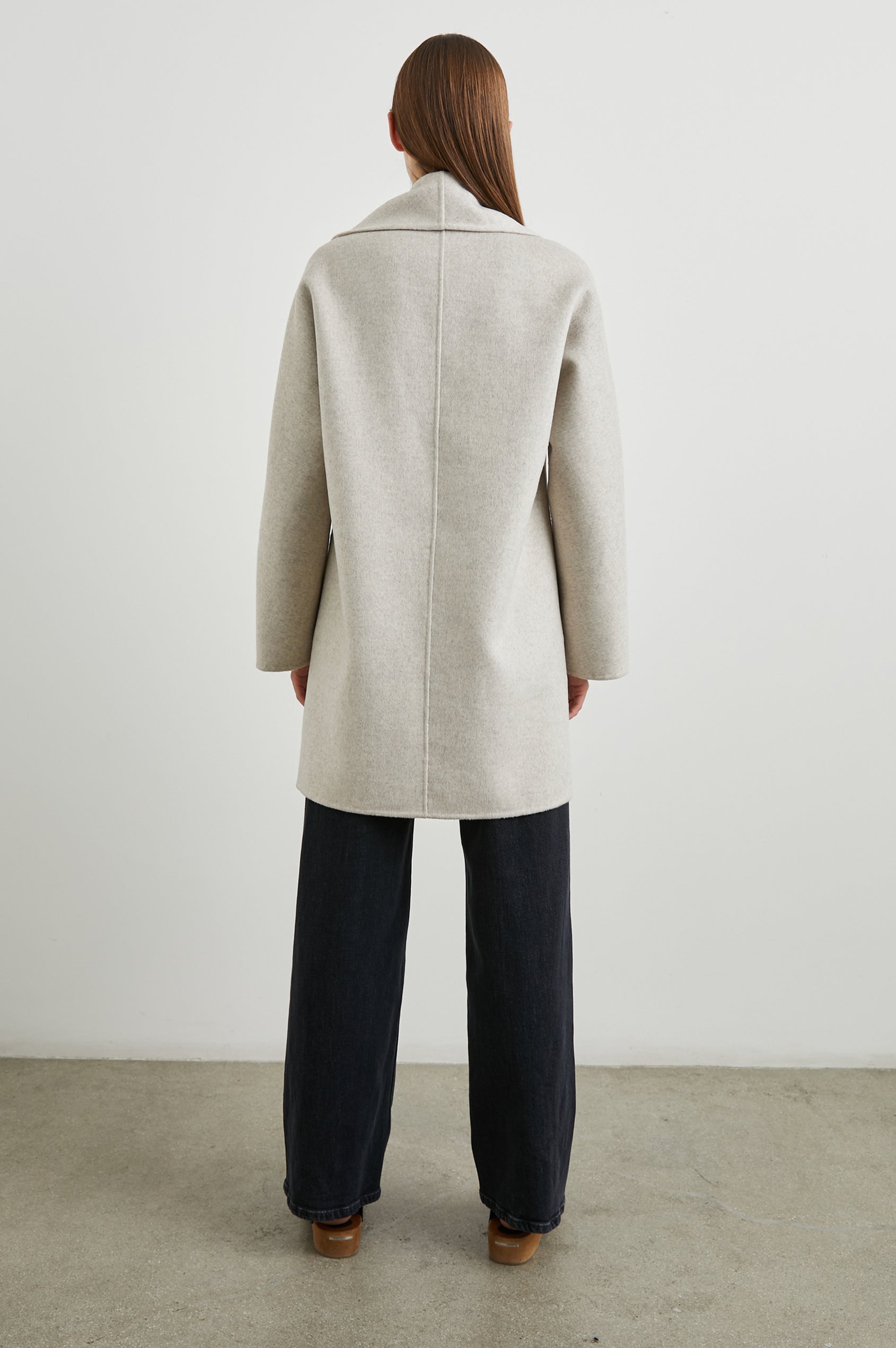 Nily Mid-Thigh Length, Double-Breasted Coat with Two Button Closure, Two Front Patch Pockets and a Shaw Collar in Oatmeal Colorway - Back Full Body View Featured on Model 