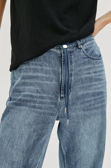 Normandie Lightweight 5-Pocket Denim Wide Leg Pant with front zipper button fly and a drawstring tie at waist in Antique Blue Colorway. Front Detail View Featured on Model.