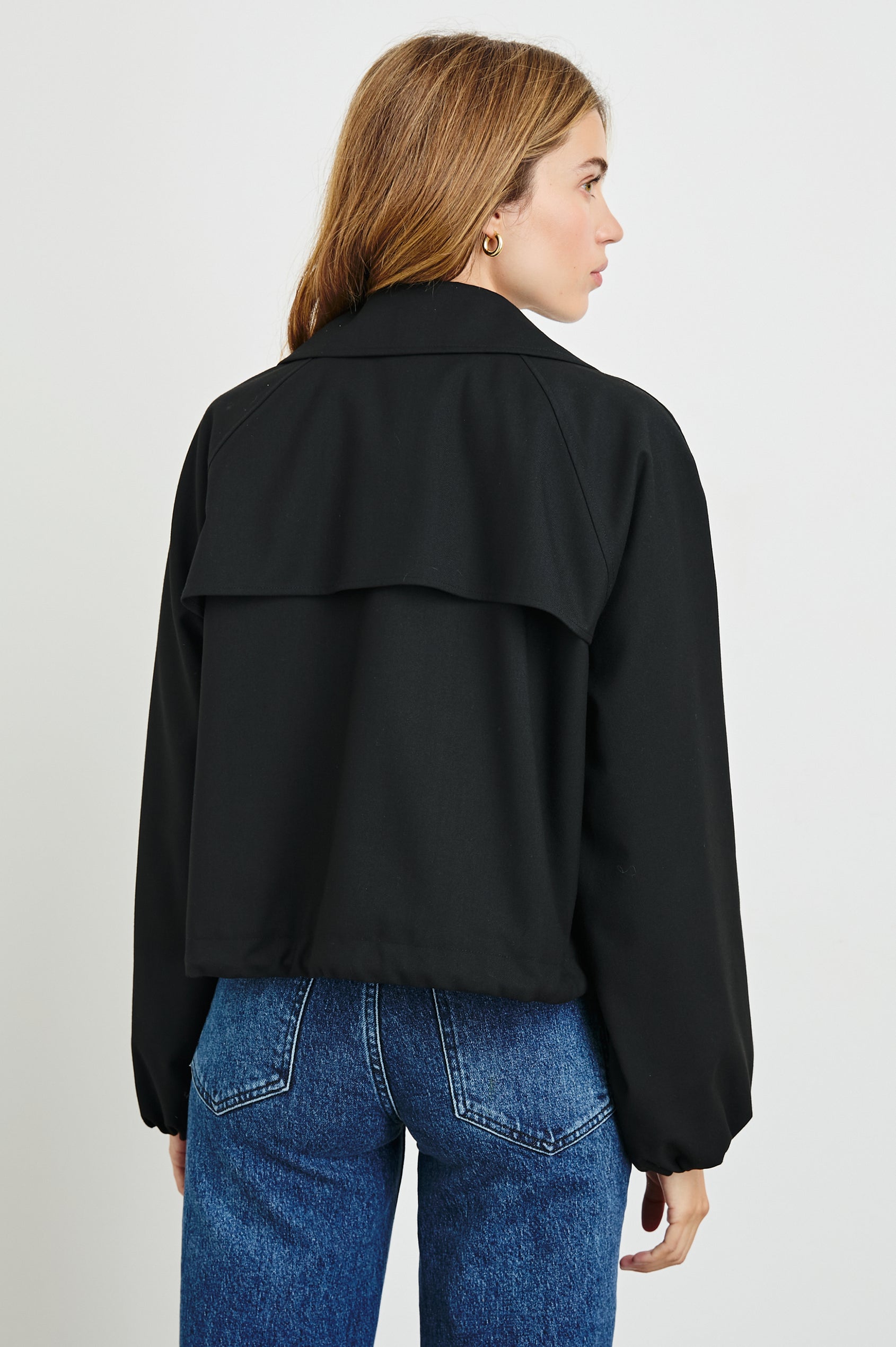 North Cropped Jacket with Button Closure, Puff Sleeves, Oversize Collar, a Toggle Hem, Two Front Pockets and a Horizontal Back Vent in Black Twill Colorway - Back View Featured on Model