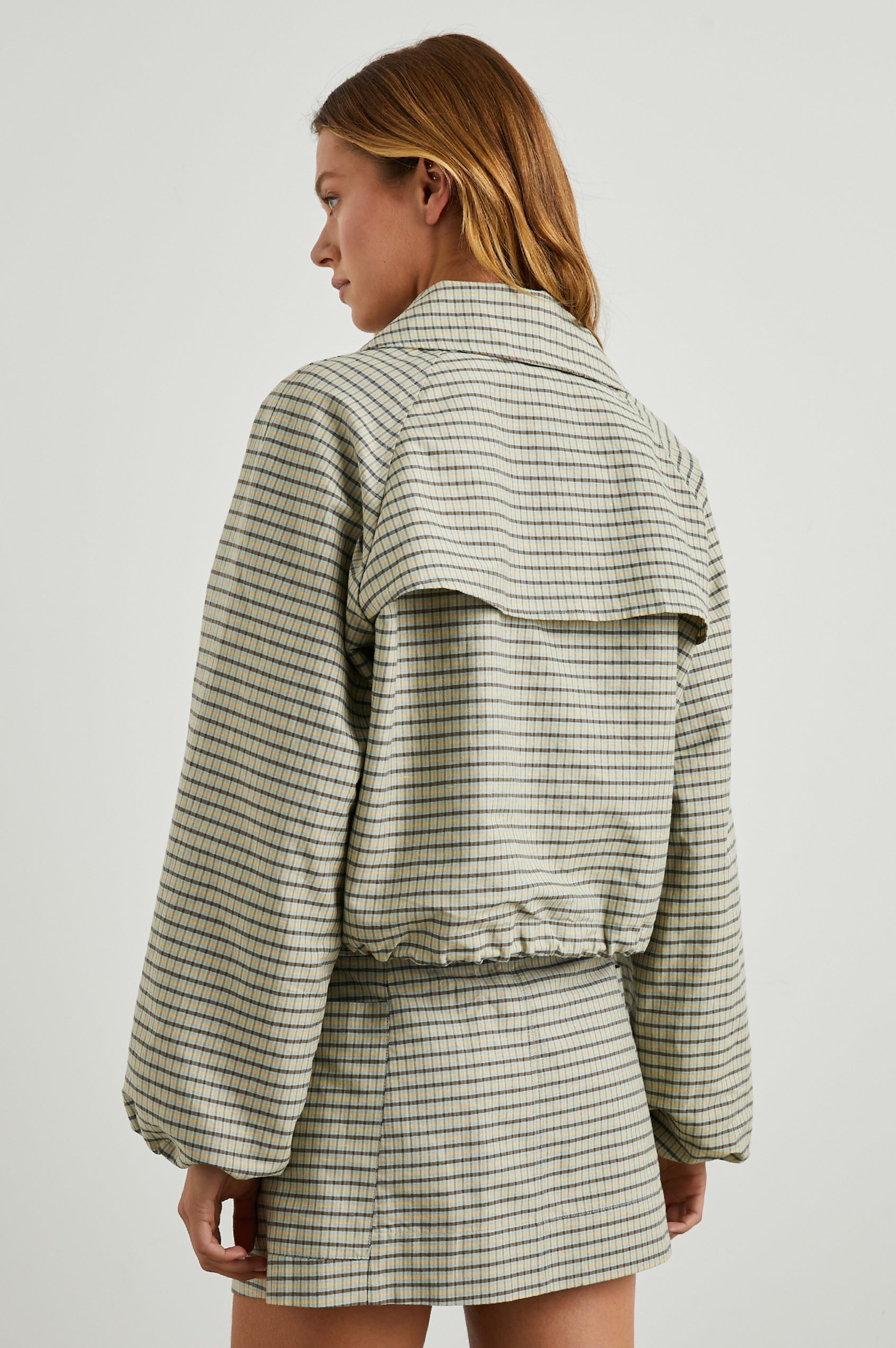 North Cropped Jacket with Button Closure, Puff Sleeves, Oversize Collar, a Toggle Hem, Two Front Pockets and a Horizontal Back Vent in Sage Mini Check Colorway, a Brown, Yellow and Sage Plaid - Back View Featured on Model