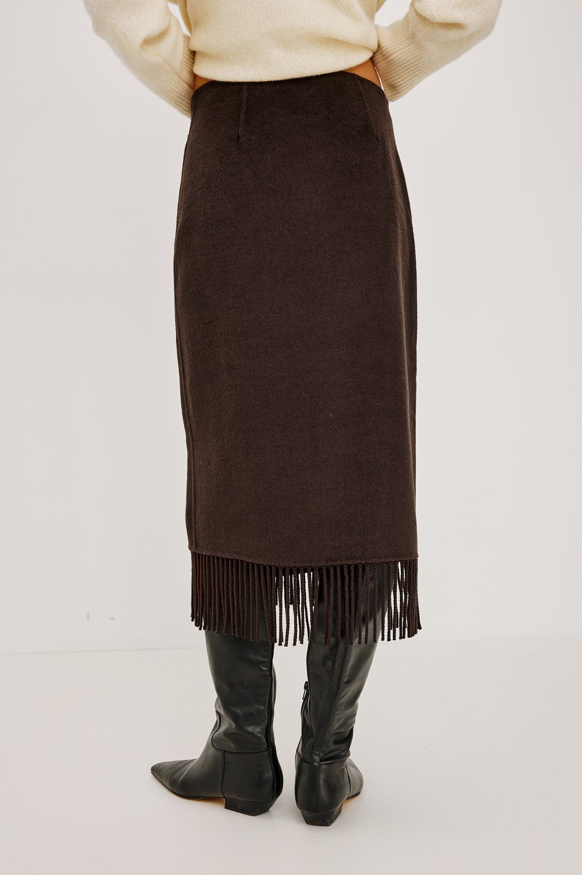 Odette Midi Skirt in Wool Blend With Wrap Design, Hidden Side Button Closure, and Fringe Hem in Black Colorway - Lower Body Back View Featured on Model