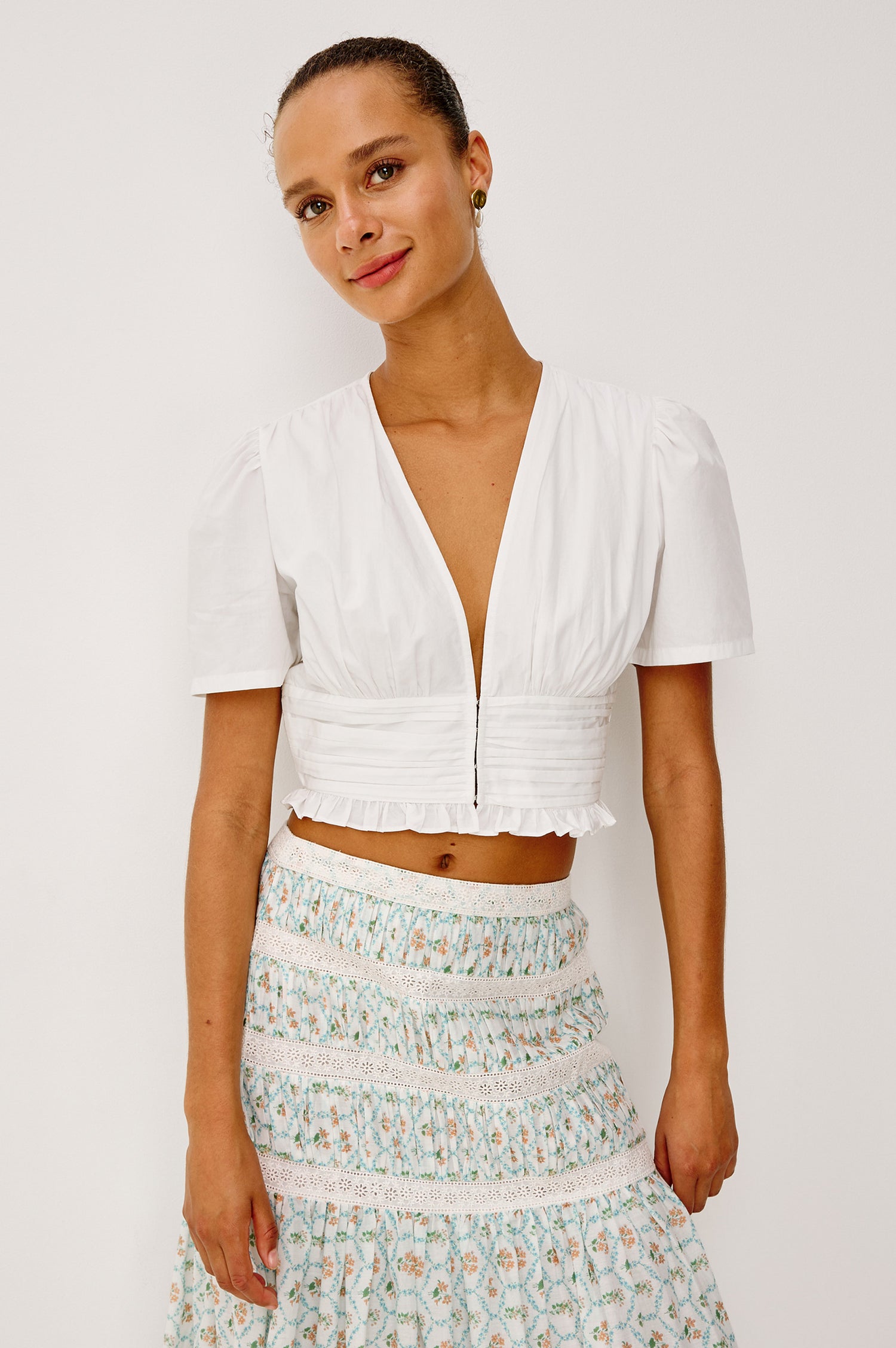 Olympia Super Croped Top in Cotton Poplin With Wide Cap Sleeves, Shirred Waist Panel, Front Hook-and-Eye Closures, V-Neckline, Wide Cap Sleeves, and is Fully Lined in White Colorway - Upper Body Front View Featured on Model