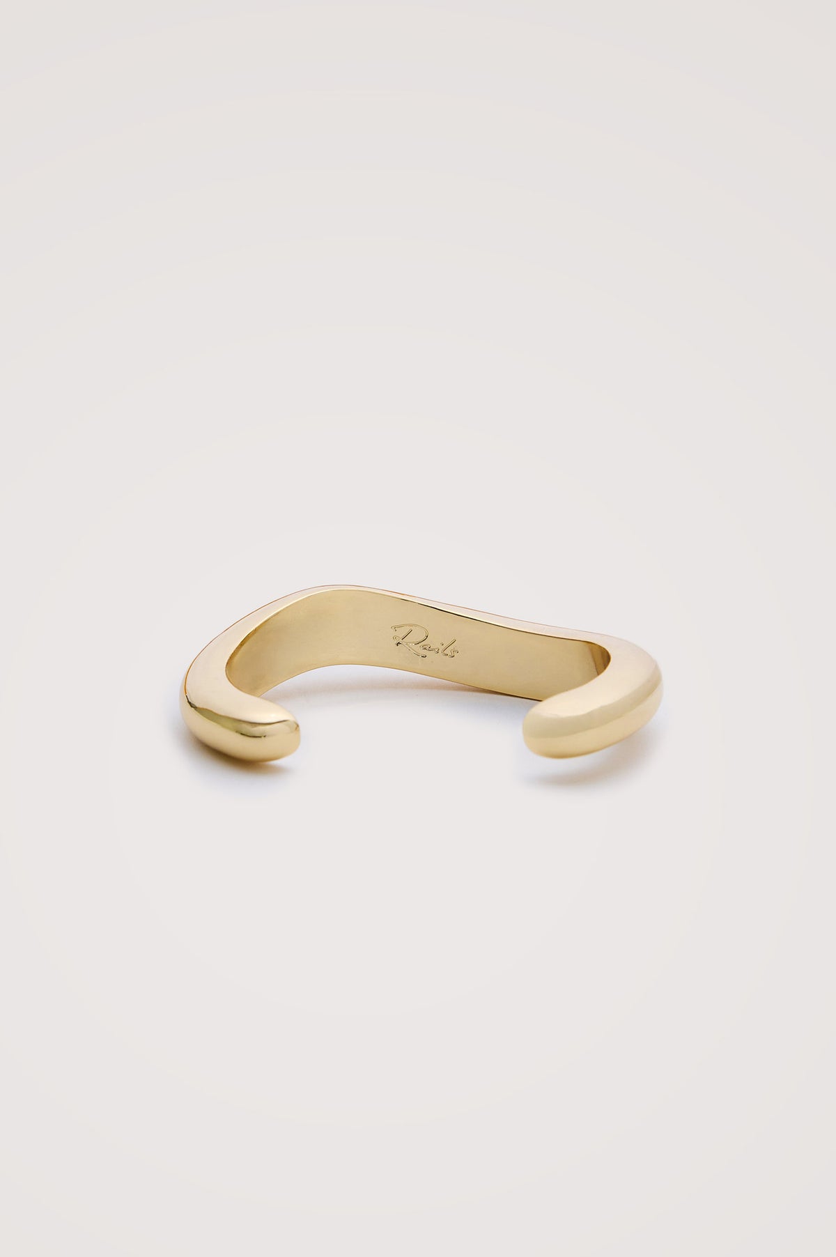 Organic Shaped Cuff Bracelet With Open Back and Engraved Interior Rails Logo in Gold Colorway - Flat Lay Close Up Product View Featured