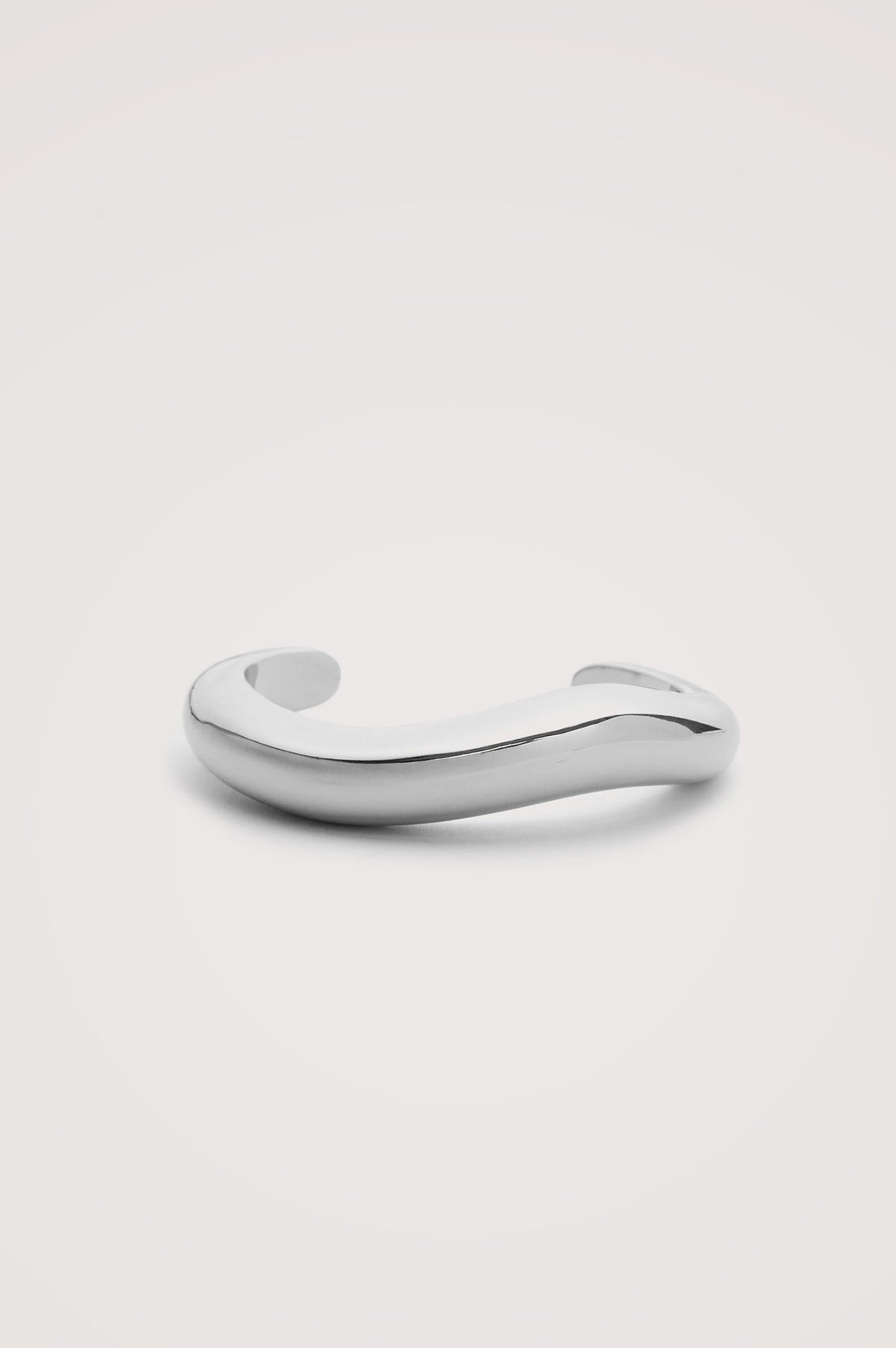 Organic Shaped Cuff Bracelet With Open Back and Engraved Interior Rails Logo in Silver Colorway - Flat Lay Close Up Product View Featured