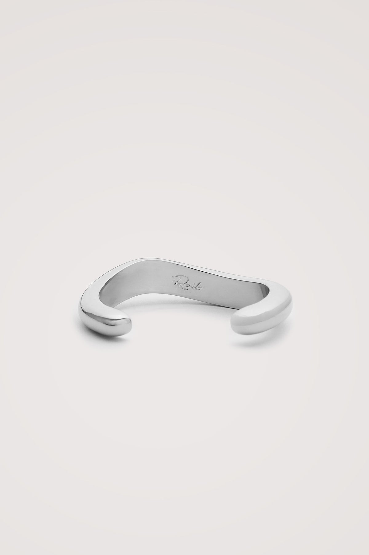 Organic Shaped Cuff Bracelet With Open Back and Engraved Interior Rails Logo in Silver Colorway - Flat Lay Close Up Product View Featured