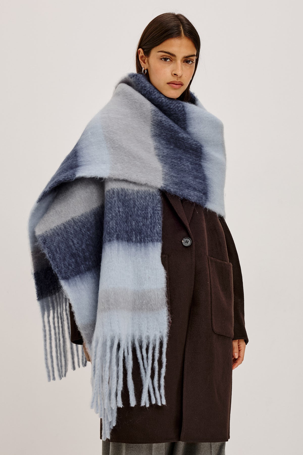 Oslo Scarf in Brushed Polyester Knit With Oversized Shape and Fringe Trim in Sky Indigo Stripe Colorway - Upper Body Front View Featured on Model.