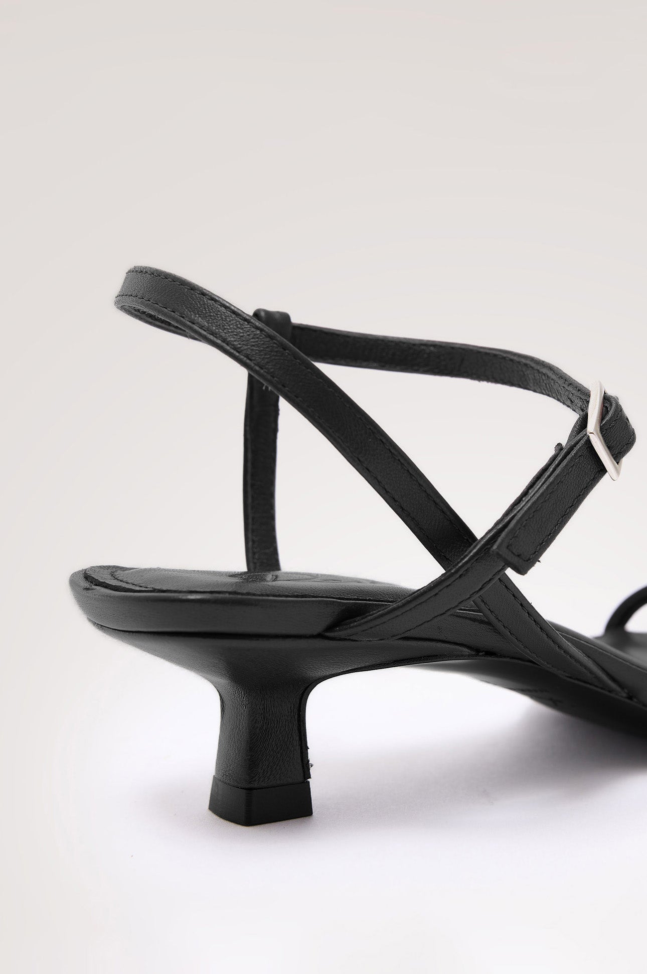 Palma Sandal Heel in Top-Grain Leather With Single Toe Strap, Adjustable Buckled Wrap Ankle Strap, and Low Heel in Black Colorway - close up back view of shoe.