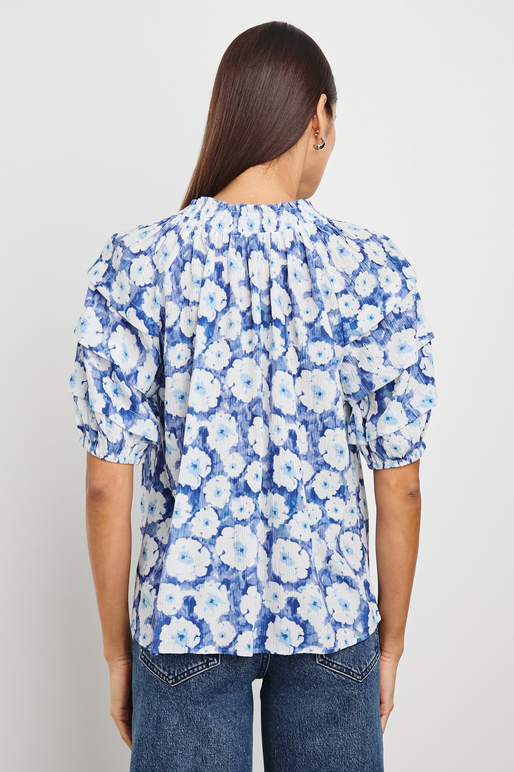 Paris Short-Sleeve Top with Shirred Collar, V-neckline with Ties, Deep Pleats on Sleeves and Elastic at the Sleeve Opening in Blue Floral Colorway, Blues and White - Back Untucked View Featured on Model
