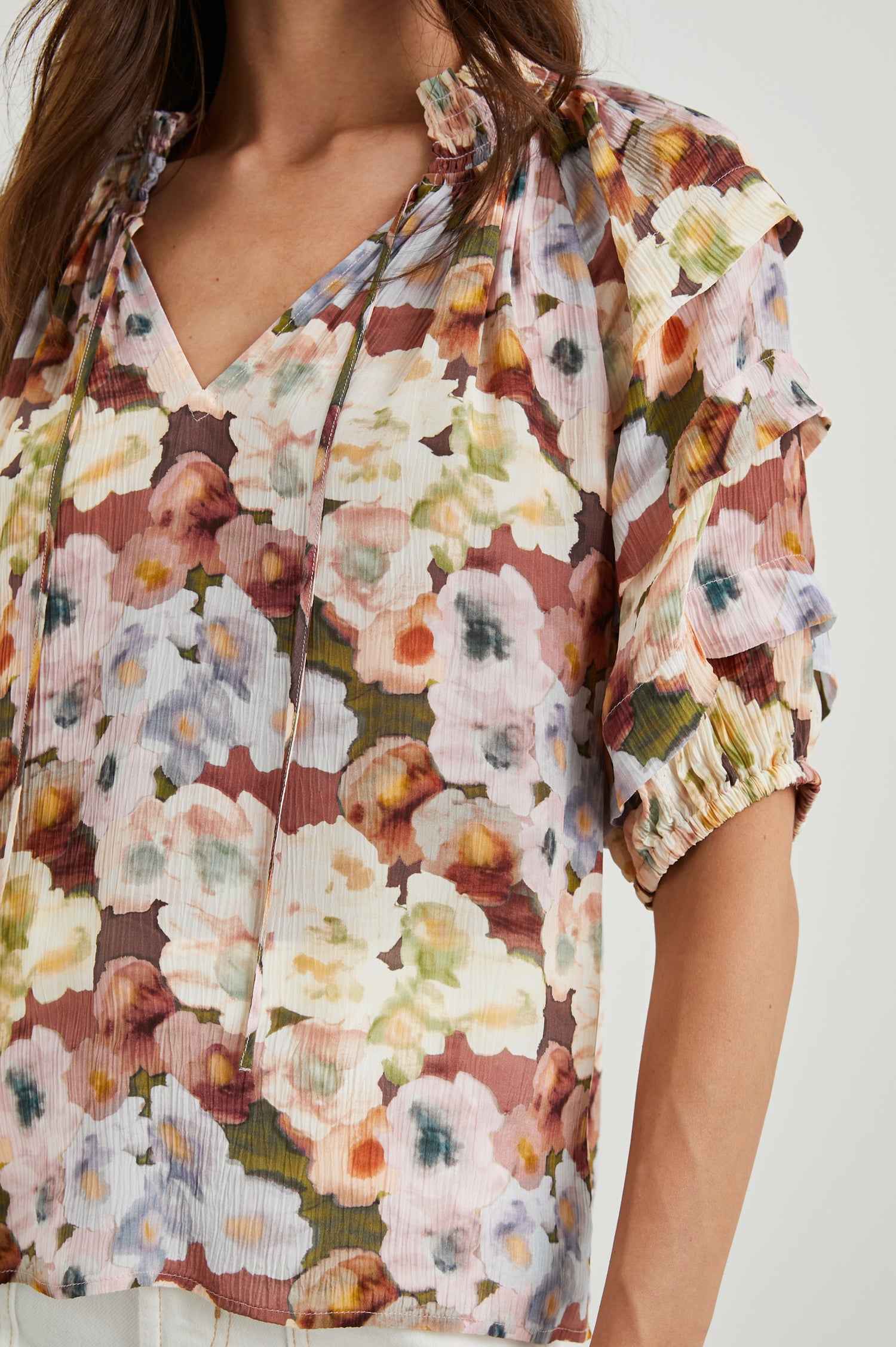 Paris Short-Sleeve Top with Shirred Collar, V-neckline with Ties, Deep Pleats on Sleeves and Elastic at the Sleeve Opening in Painted Floral Colorway, with browns, yellows, and blues - Front untucked View Featured on Model