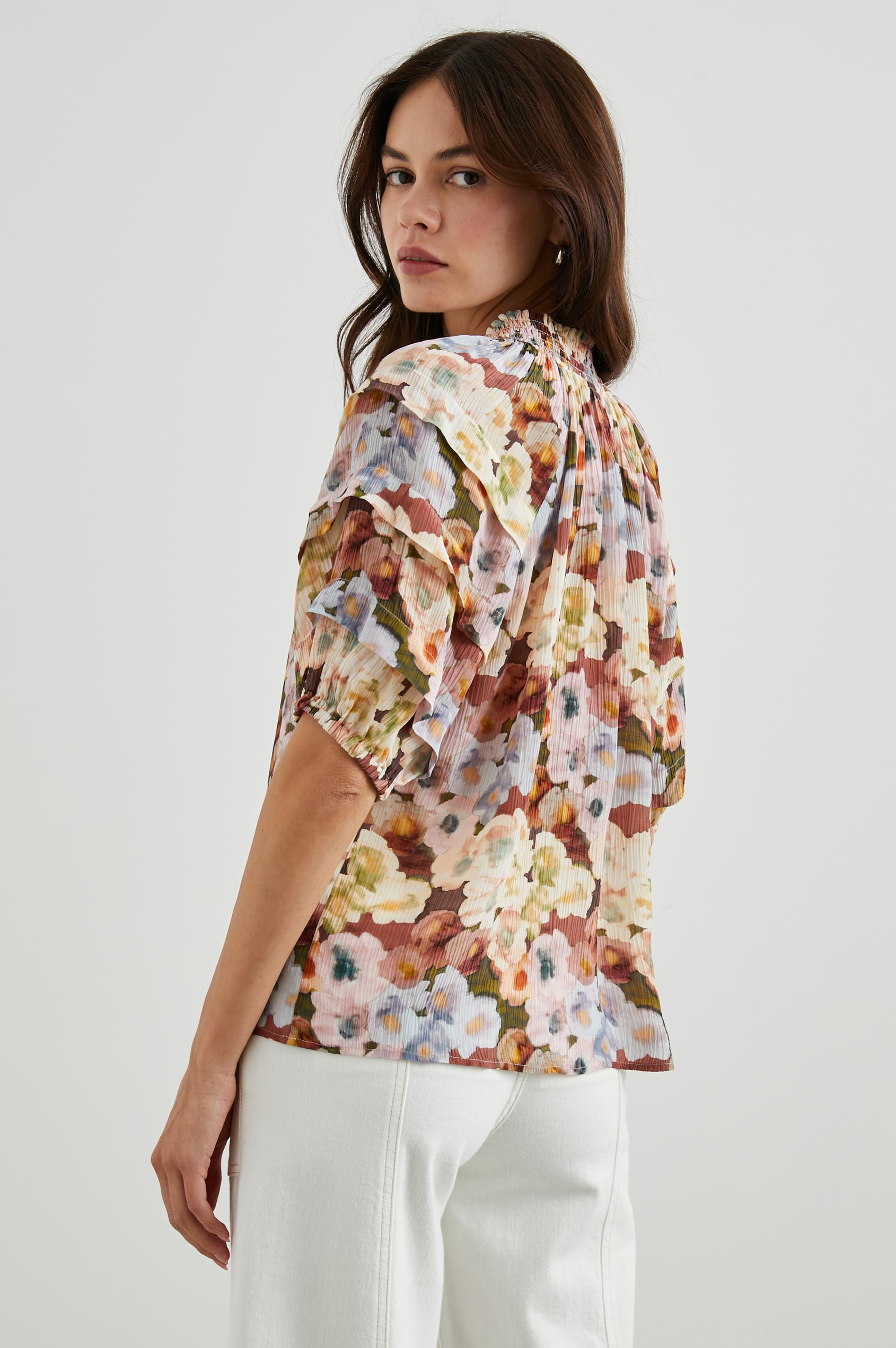 Paris Short-Sleeve Top with Shirred Collar, V-neckline with Ties, Deep Pleats on Sleeves and Elastic at the Sleeve Opening in Painted Floral Colorway, with browns, yellows, and blues - Back untucked View Featured on Model