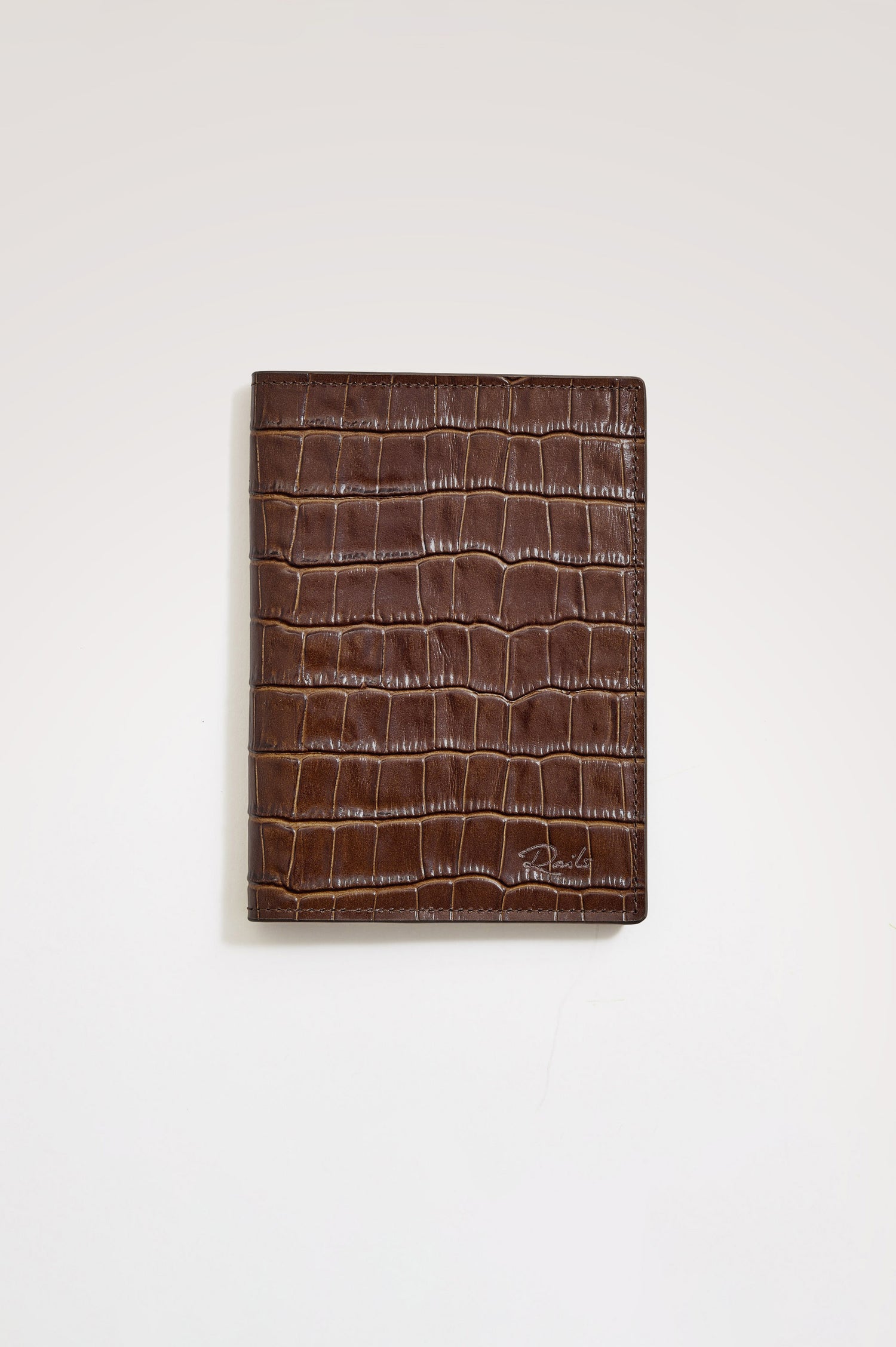 Passport Holder in Croc-Embossed Spanish Leather With Five Card Slots, Two Side Pockets, and Embossed Rails Logo in Dark Brown Croc Embossed Colorway - Front view flatlay featured.