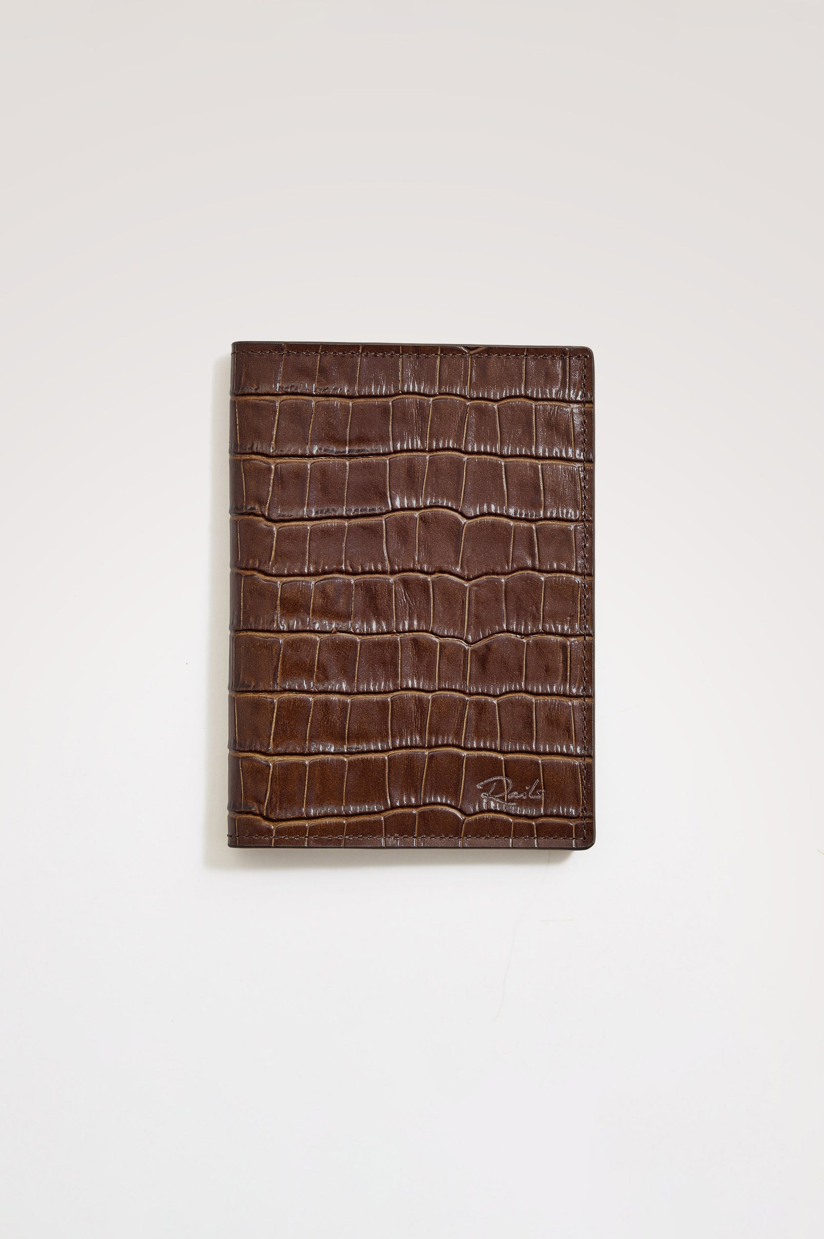 Passport Holder in Croc-Embossed Spanish Leather With Five Card Slots, Two Side Pockets, and Embossed Rails Logo in Dark Brown Croc Embossed Colorway - Front view flatlay featured.