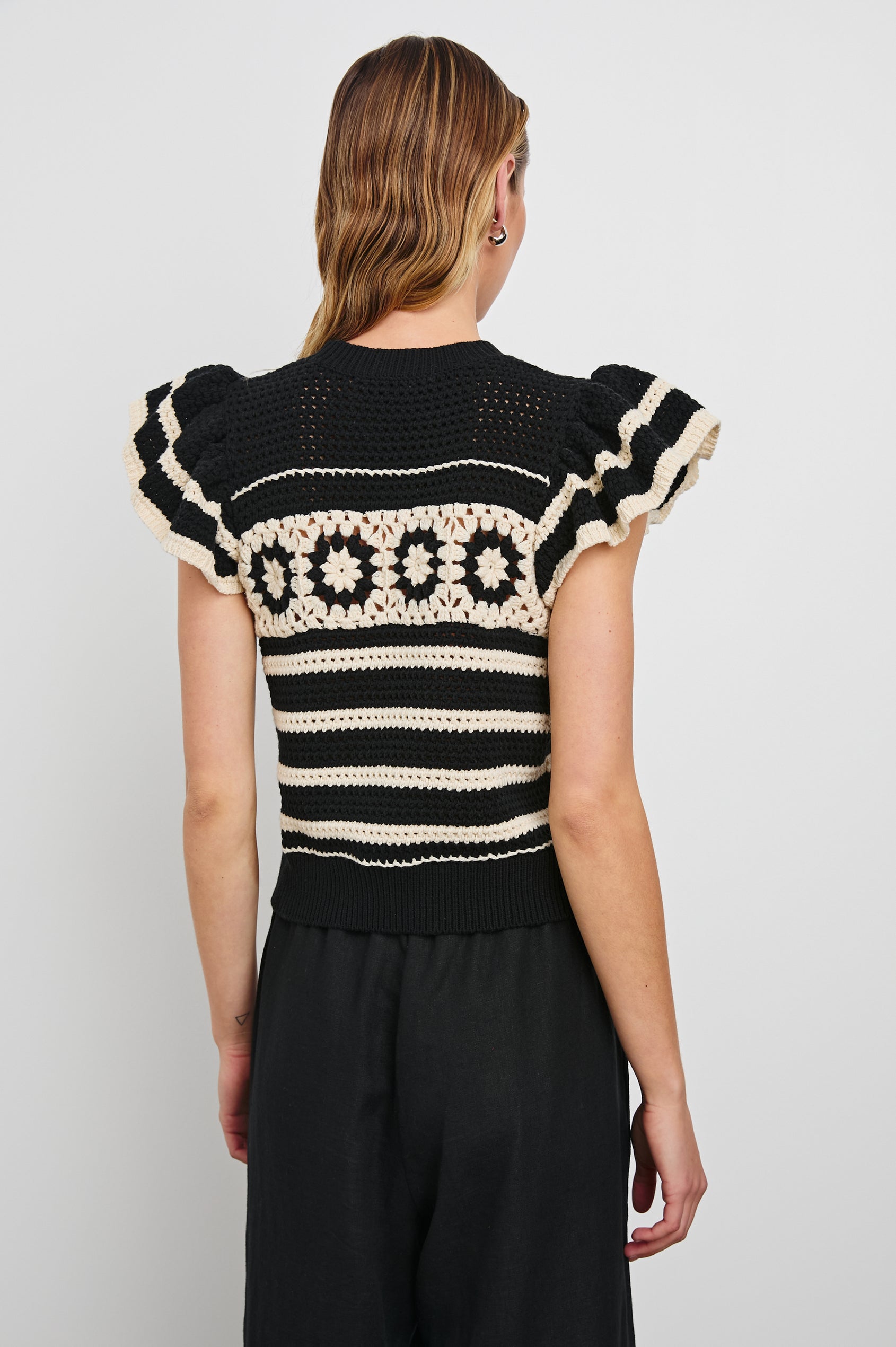 Penelope Crochet Top with Flutter Sleeves and Ribbed Hem in Black Ivory Stripe Colorway, Horizontal Stripes with Contrasting Knit Flowers Across the Chest - Back View Featured on Model