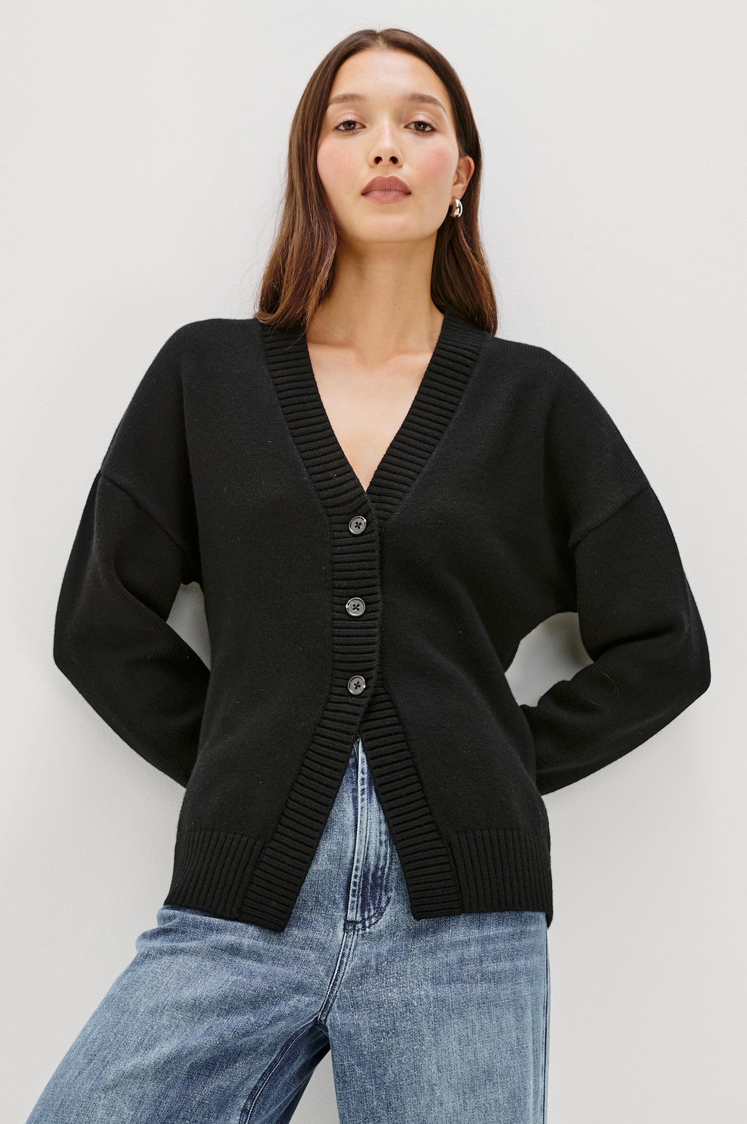 Longline cardigan in a cotton-wool blend in Black Colorway. The design features drop shoulders and a front cutaway detail, creating a soft, relaxed, and flattering silhouette. Front View on Model.