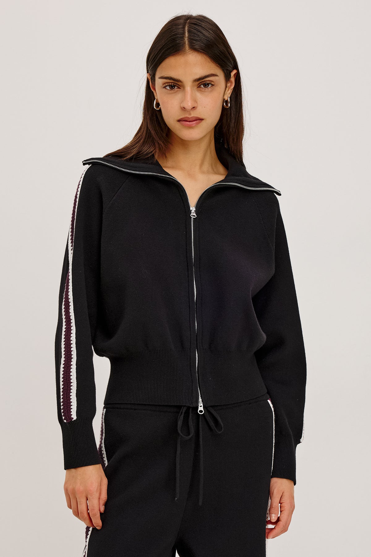 Piper Track Sweater Jacket in Cotton-Blend Knit With Shawl Collar, Double-Zip Front, and Contrast Crochet Stripes Down Long Sleeves in Black Merlot Stripe Colorway - Upper Body Front View Featured on Model.