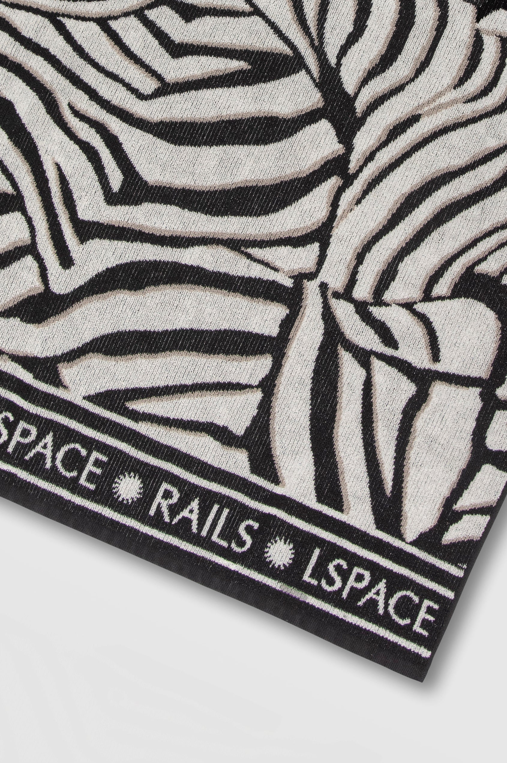 Playa Blanca Towel in Playa Blanca black and white abstract print with Rails and LSpace logo on the edge - close up of logo