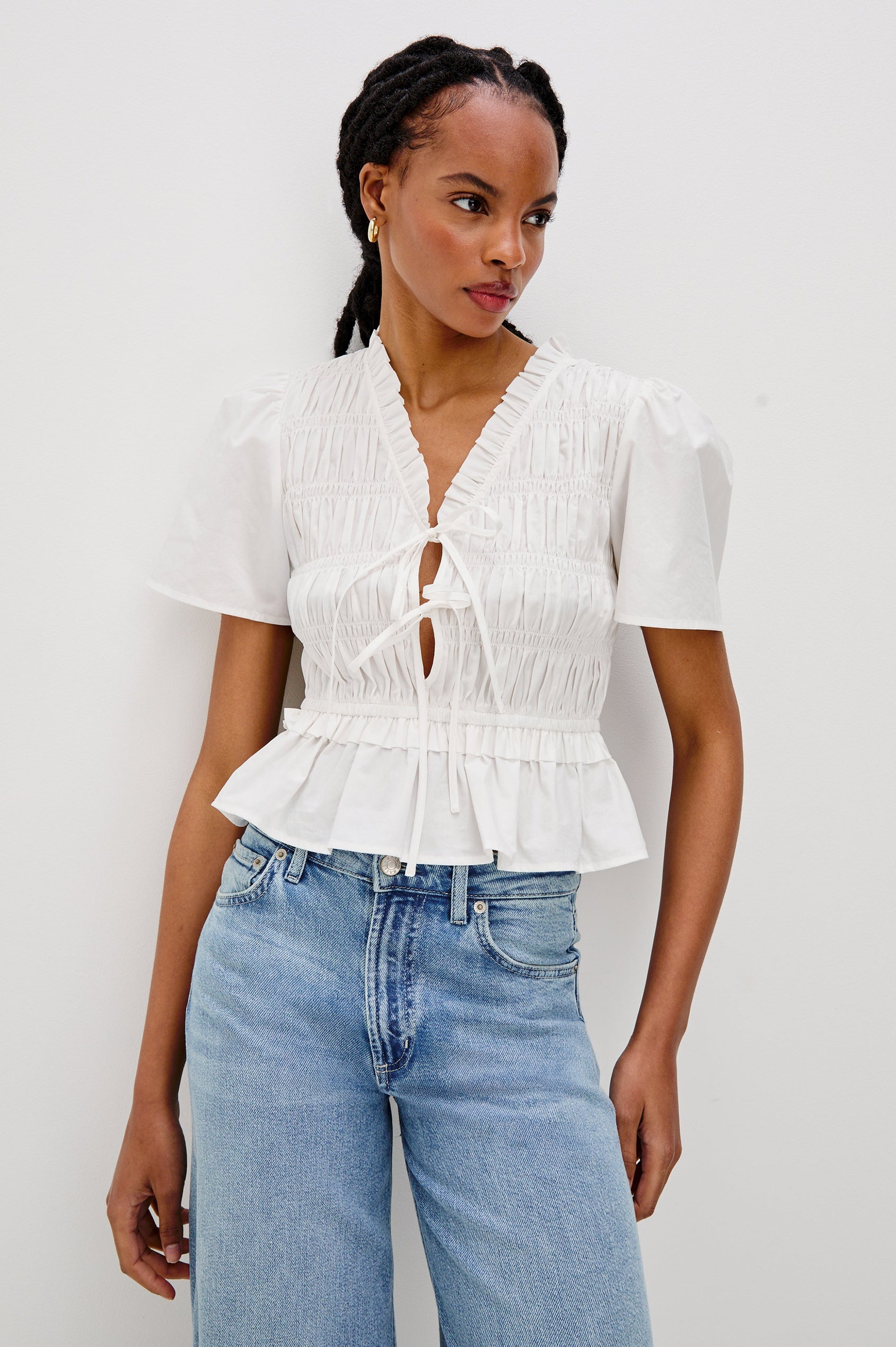 Portia V-Neck Tie Front Top with Short Puff Sleeves and a Ruffled Peplum Hem in White Colorway. Front View Shown on Model.
