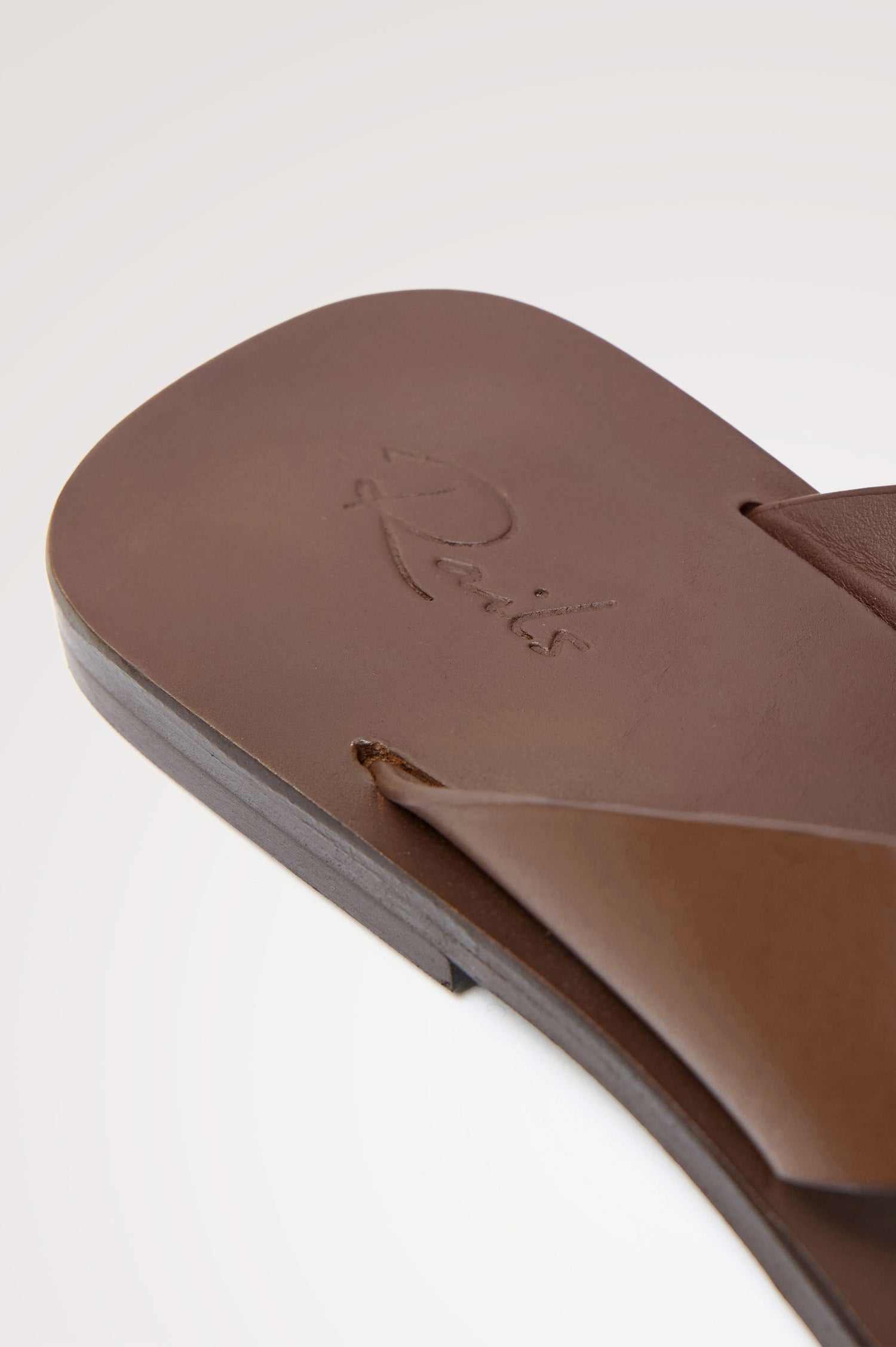 Porto Thong Sandal in Leather With Square Toe and Cushioned Footbed With Branded Embossed Detail in Dark Brown Colorway - Close Up View Featured