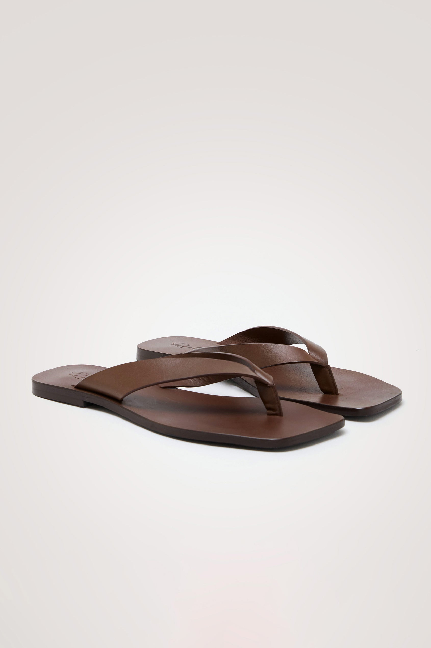 Porto Thong Sandal in Leather With Square Toe and Cushioned Footbed With Branded Embossed Detail in Dark Brown Colorway - Top View Featured on Model