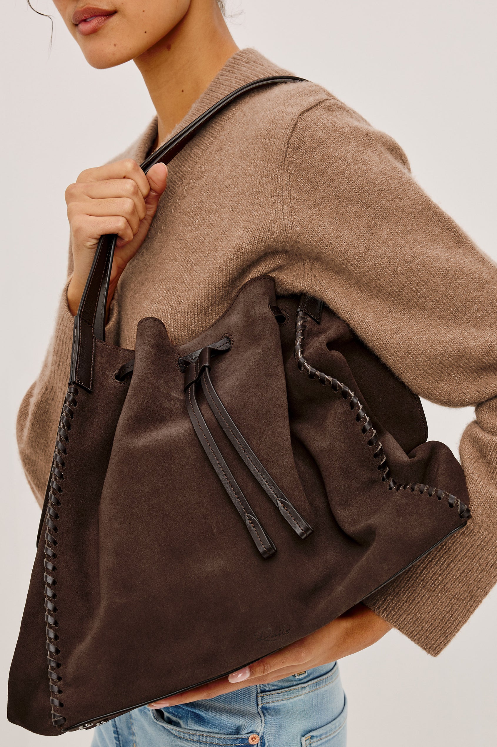 Prato Bucket Tote in Suede With Whipstitch Trim, Fixed Top Straps, Drawcord Closure, Interior Zip Pocket, Interior Slip Pocket in Dark Brown Suede Colorway - Side Stylized Product View Featured