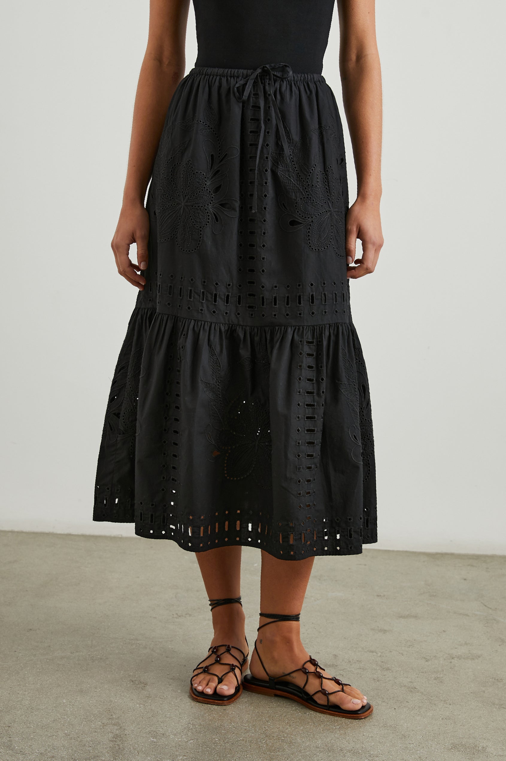 Prina Tiered Midi Skirt with a Drawstring Waist and Floral and Geometric Eyelet Details in Black Colorway - Front View Featured on Model