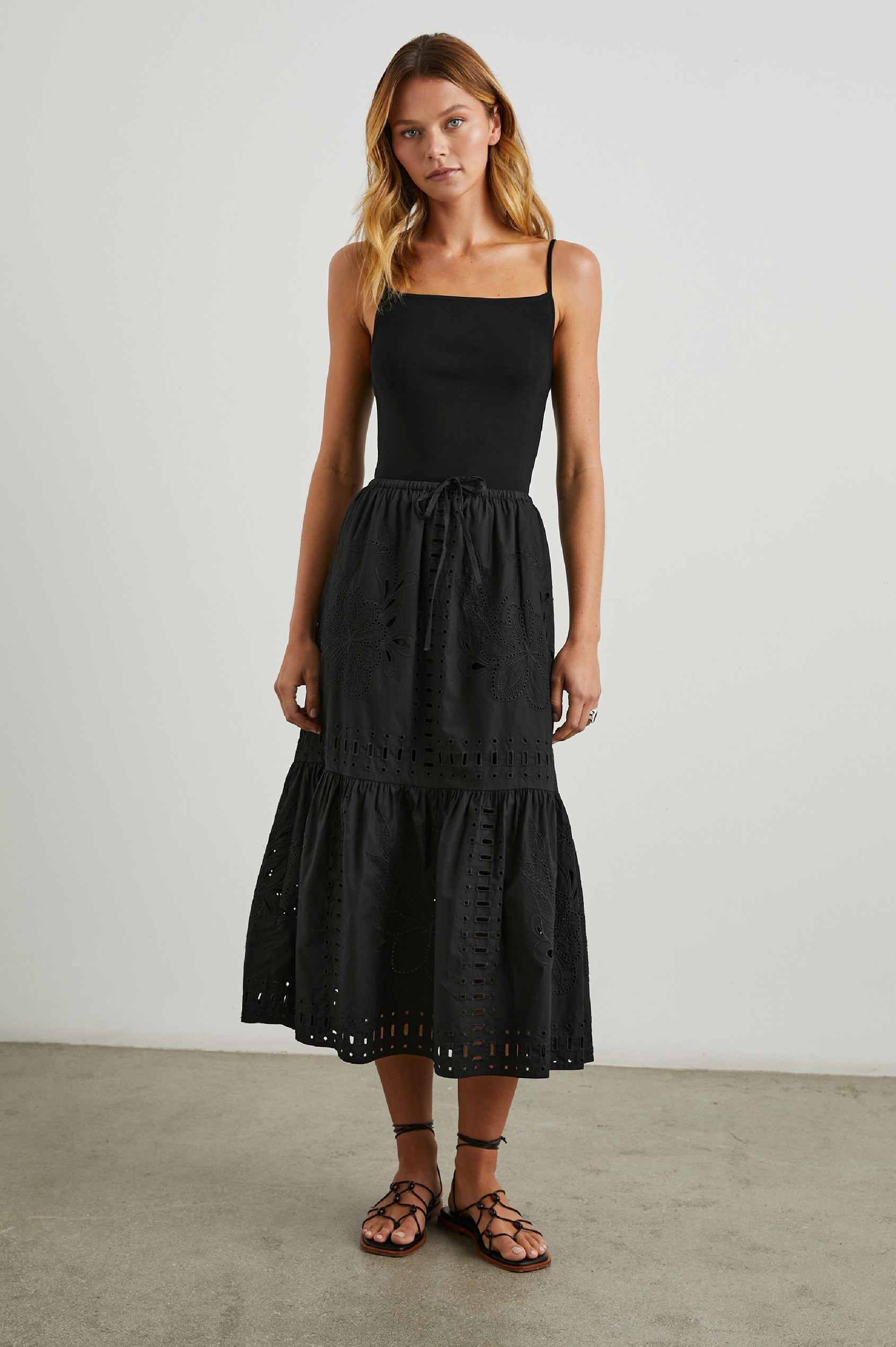 Prina Tiered Midi Skirt with a Drawstring Waist and Floral and Geometric Eyelet Details in Black Colorway - Front Full Body View Featured on Model