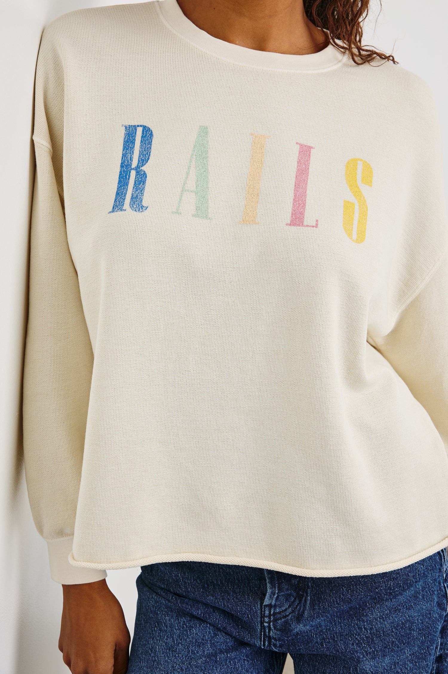 Rails Signature Long-Sleeve Sweatshirt with a Crew Neck, Raw Hem, Shirring Above Cuff, and the Text, Rails, in Ivory Colorway, with Multi Colored Text - Front View Featured on Model 