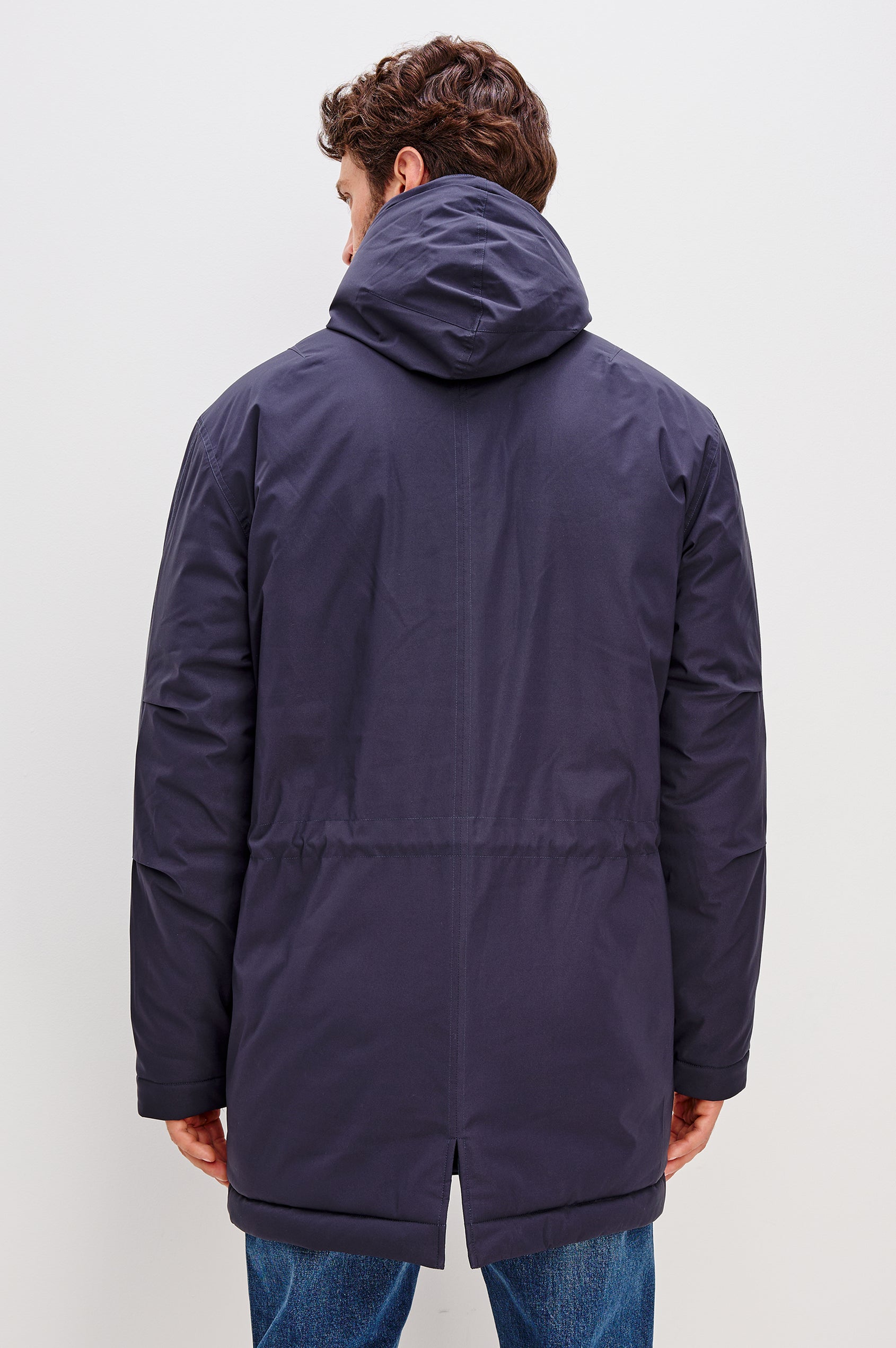 Rainier is a hooded parka coat, water-resistant and features hand warming pockets with snap closure, drawcord at hood and waist for sinching effect and a double flap center front closure and back seam vent in Navy colorway. Front view featured on model.