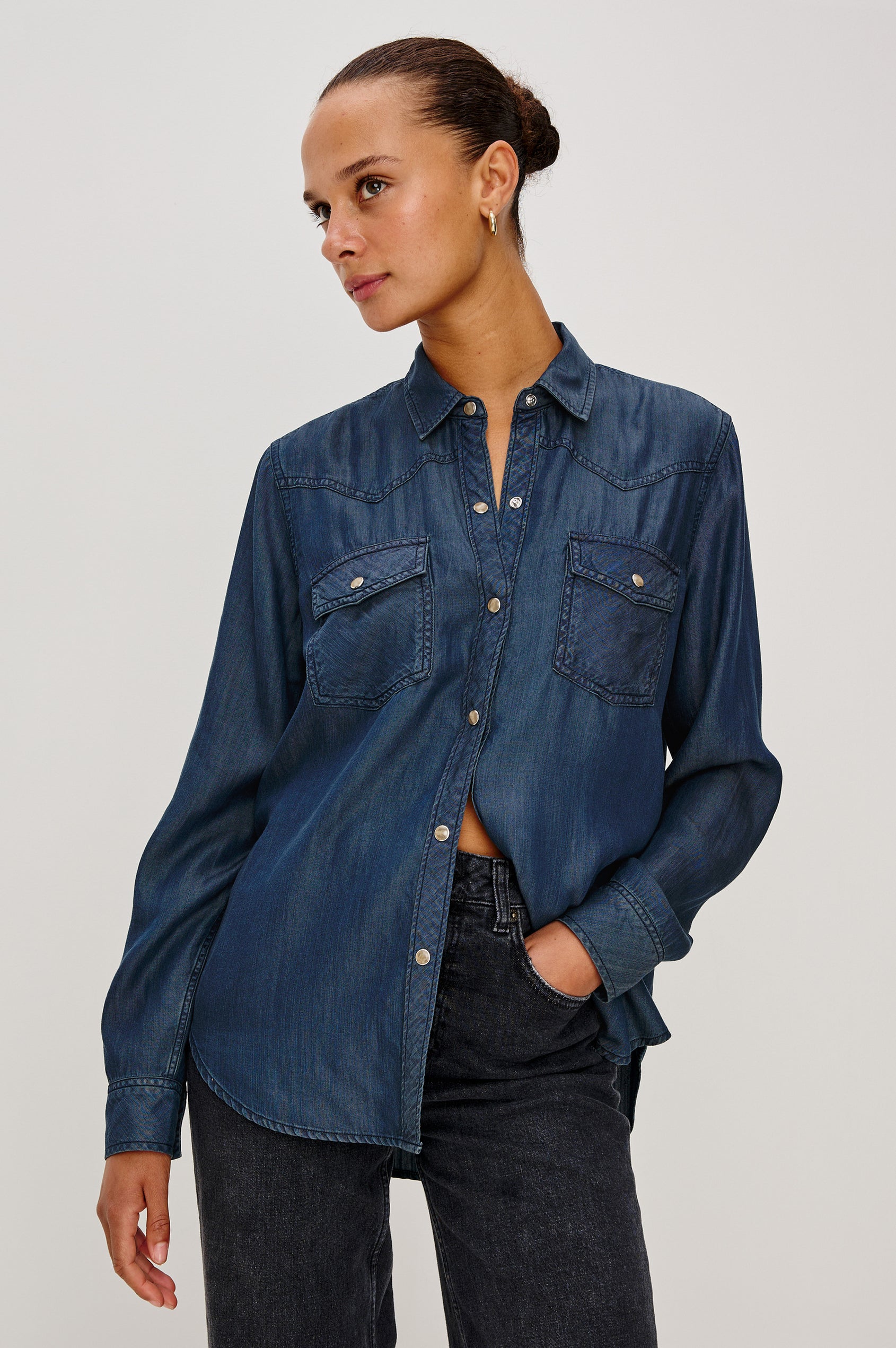 Remi is a utility-style Tencel denim shirt with a relaxed fit. The shirt features a notched collar, two front flap pockets, and faux horn buttons etched with a logo in Oceana dark blue colorway - Front View Featured on Model