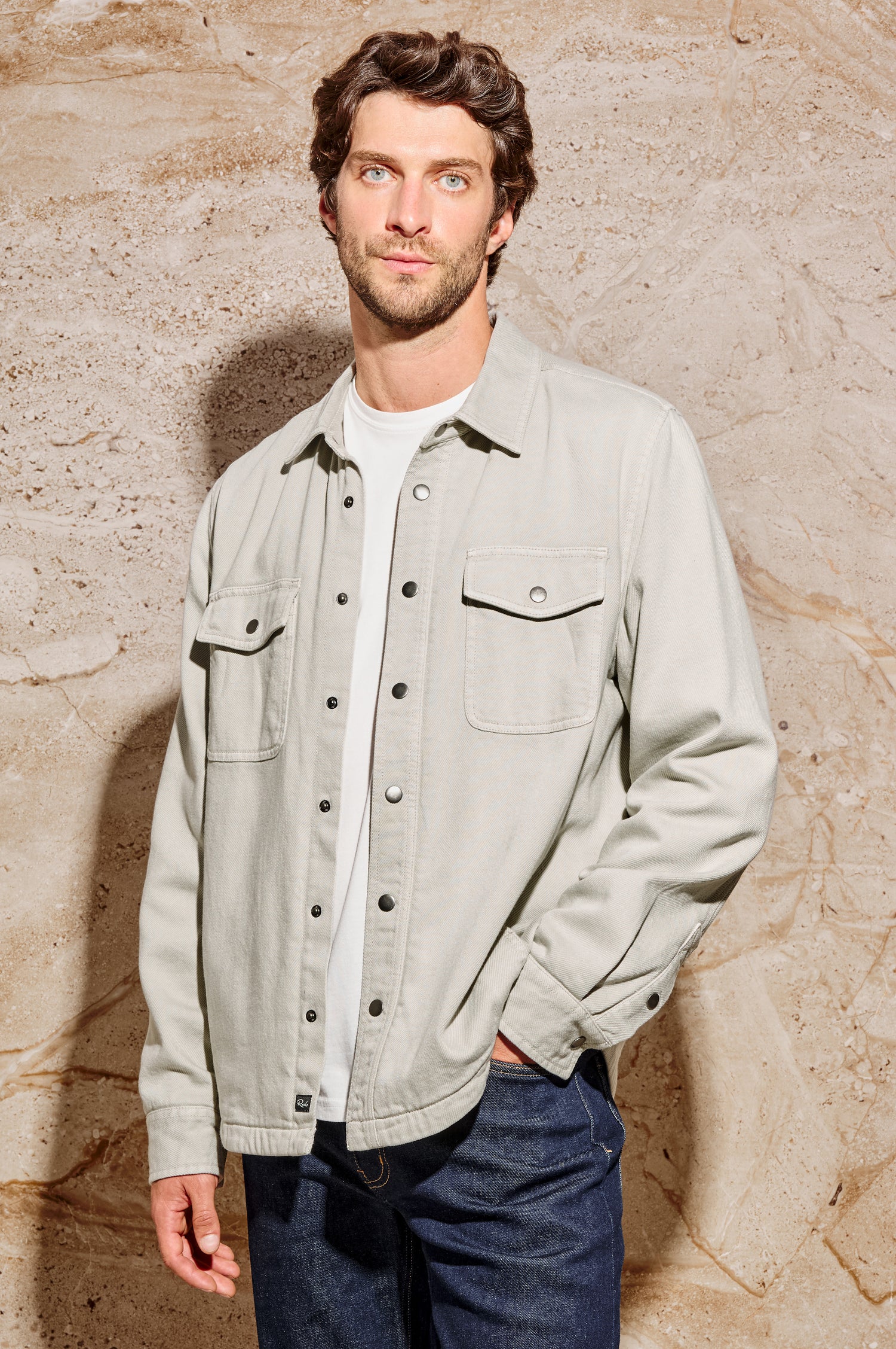 Rhett is a collared snap front shirt jacket with two chest pockets, side pockets and adjustable sleeve plackets in Stone colorway. Front view featured on model.