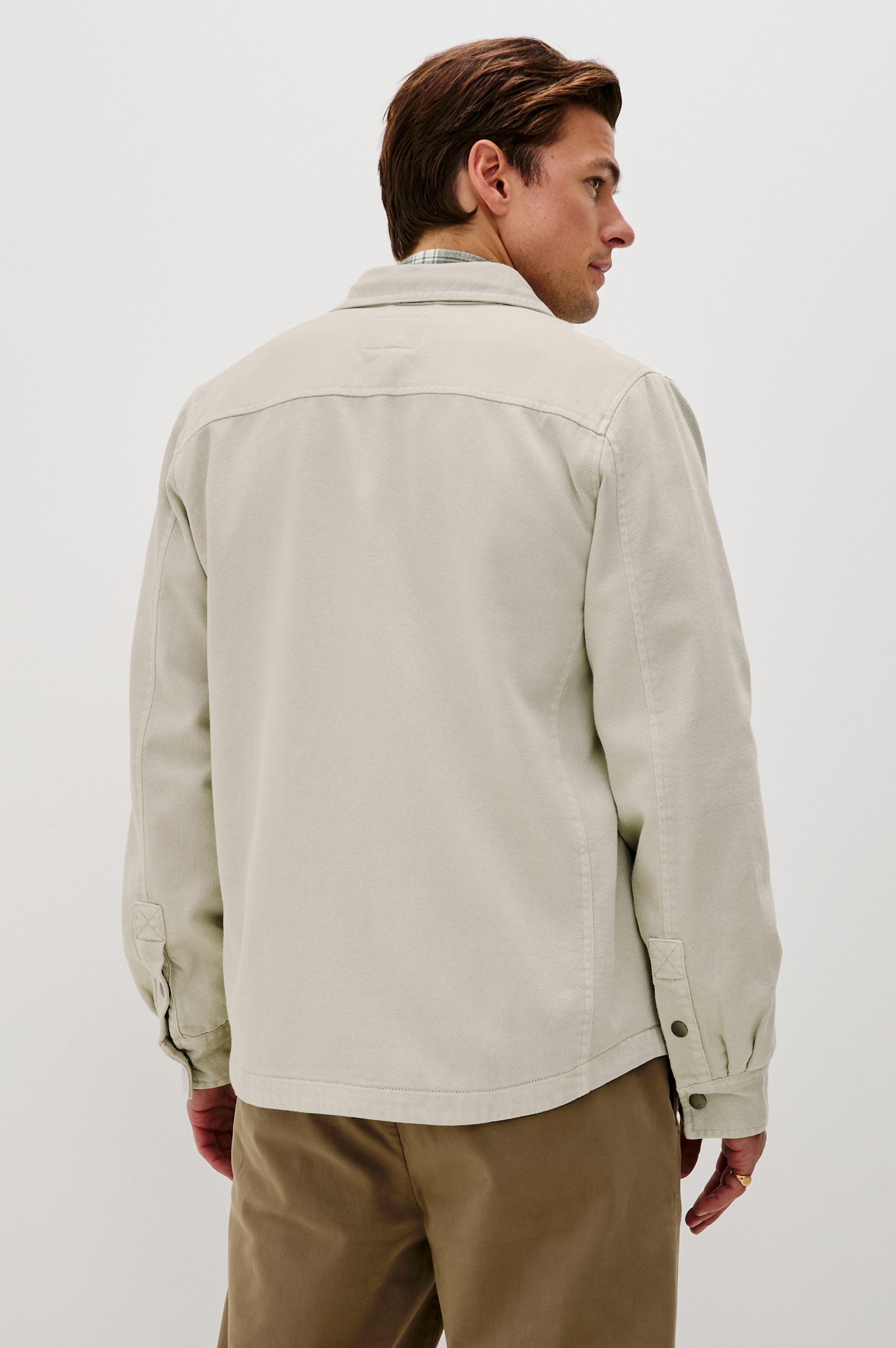 Rhett is a collared snap front shirt jacket with two chest pockets, side pockets and adjustable sleeve plackets in Stone colorway. Back view featured on model.