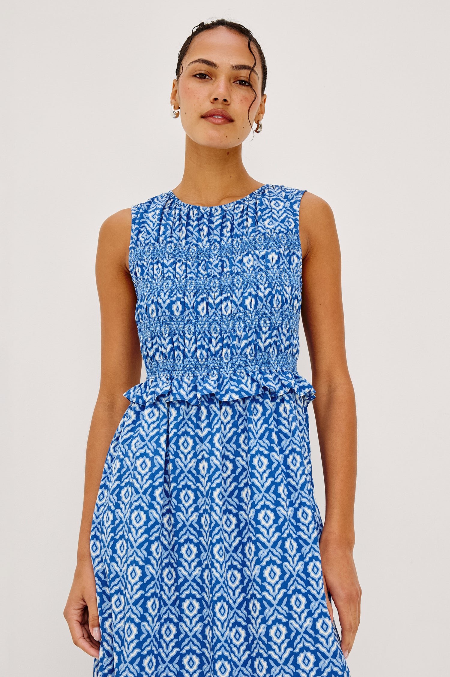 Rialto Midi Dress in Cotton Poplin With High Neckline, Smocked Bodice, Sleeveless Cut, Ruffle Trim, and Tiered Hem in Blue Ikat Colorway - Upper Body Front View Featured on Model