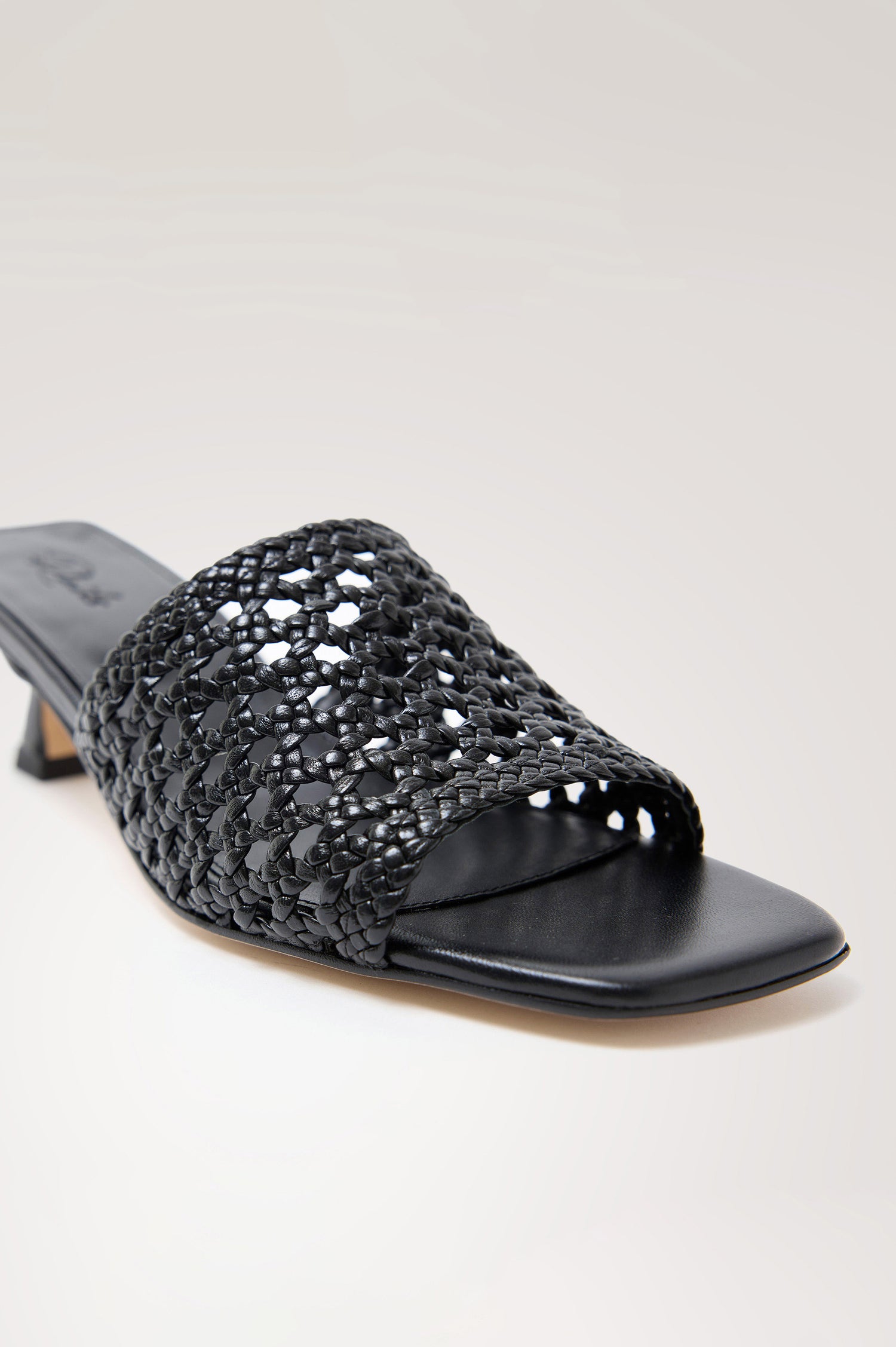 Rimini Mule Heel in Leather With Woven Upper, Square Toe, and Cushioned Footbed With Branded Embossed Detail in Black Colorway - Close Up View Featured