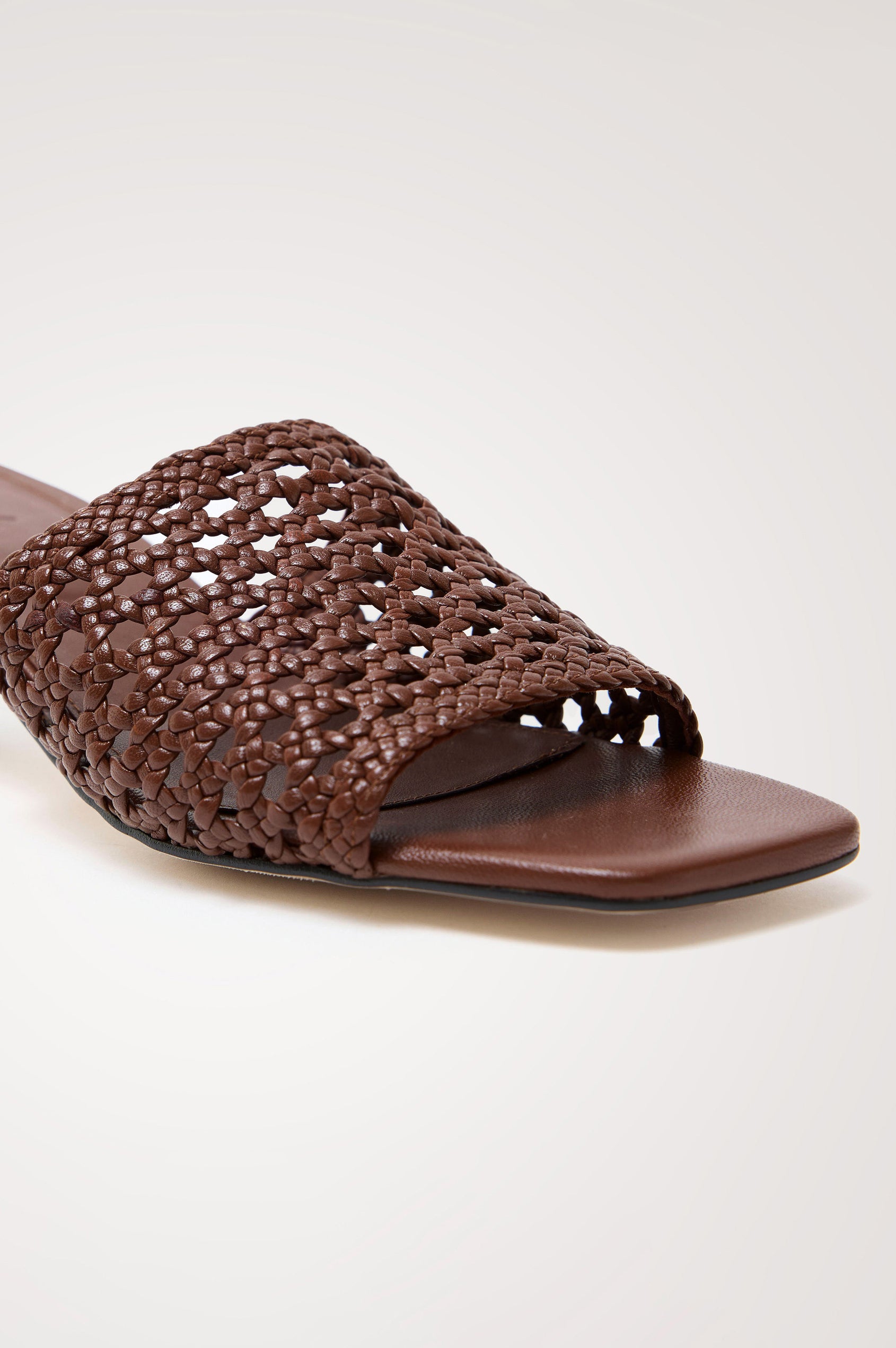 Rimini Mule Heel in Leather With Woven Upper, Square Toe, and Cushioned Footbed With Branded Embossed Detail in Dark Brown Colorway - Close up View Featured