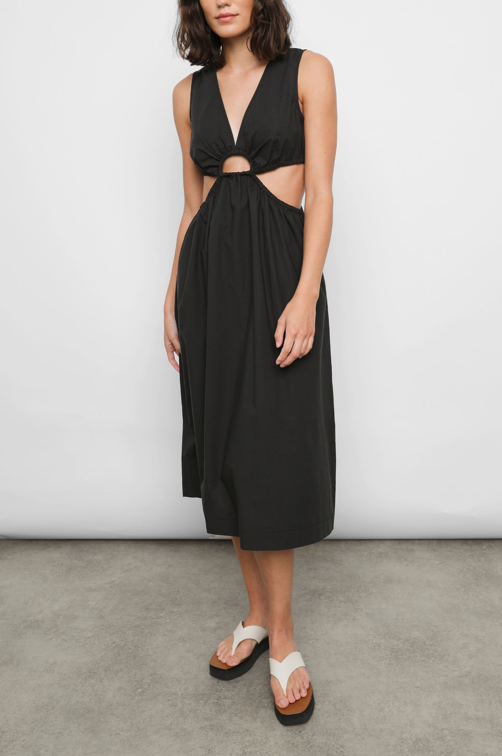 Rizo Sleeveless Midi Dress with Wide Shoulder Straps, a Deep V Neck with a Cutout, and Cutouts Beneath the Bust and Circling to the Back in Black Colorway - Front Full Body View Featured on Model  
