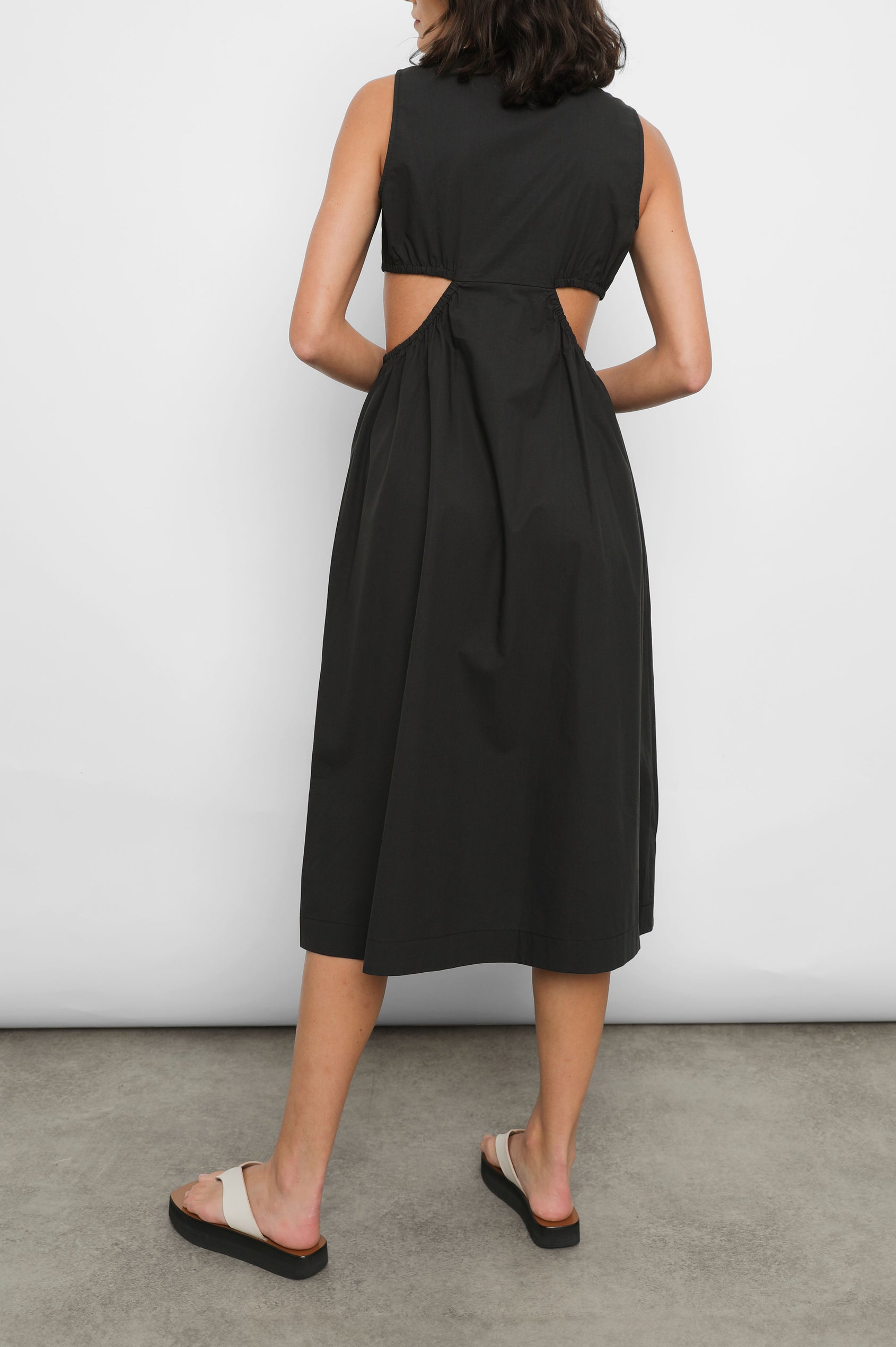 Rizo Sleeveless Midi Dress with Wide Shoulder Straps, a Deep V Neck with a Cutout, and Cutouts Beneath the Bust and Circling to the Back in Black Colorway - Back Full Body View Featured on Model  