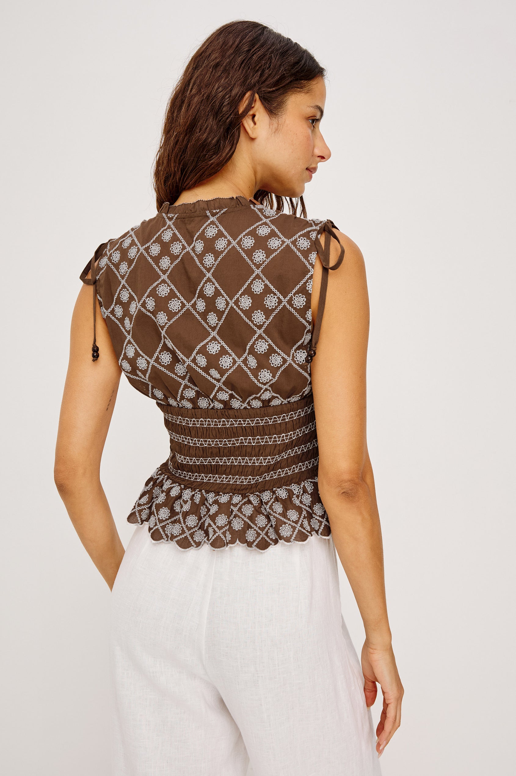 Rizzo Sleeveless Top in Cotton Voile With V-Neckline, Shoulder Ties, Ruffle Trim, Smocked Waist, and Peplum Hem in Cocoa Daisy Embroidery Colorway - Upper Body Back View Featued on Model