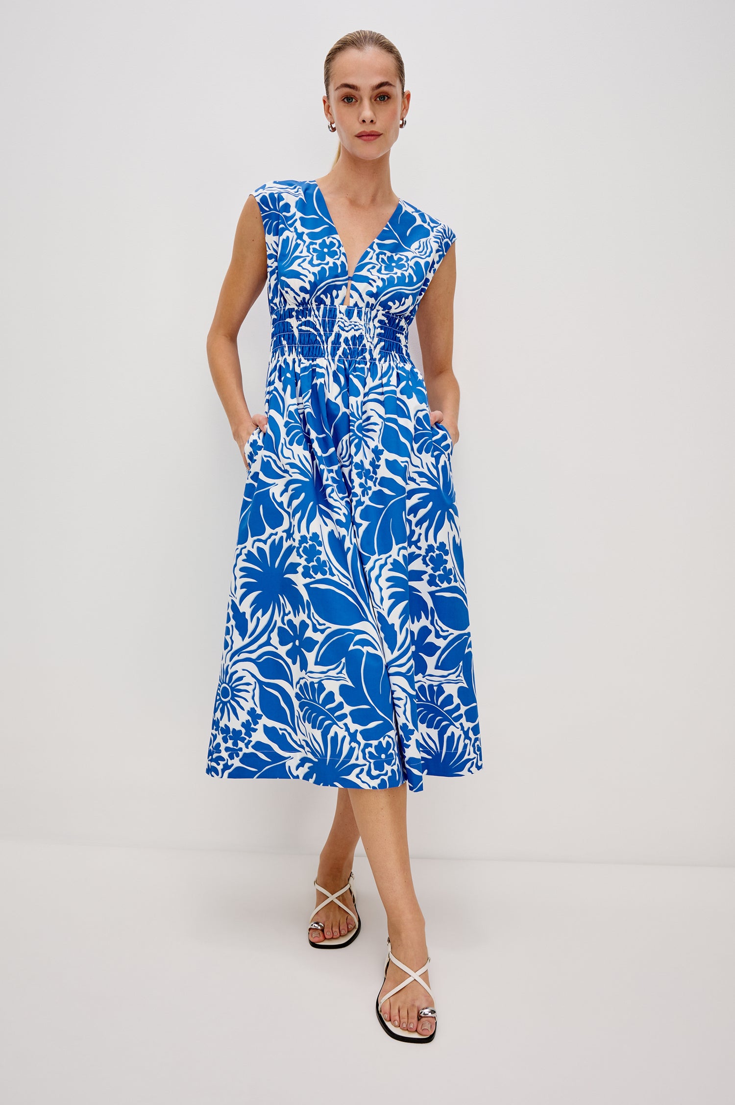 Roxanne A-Line Midi Dress with Smocked Waist, V-Neck, Cap Sleeve and Side Pockets in Blue Riviera Colorway. Full Body Front View Shown on Model.