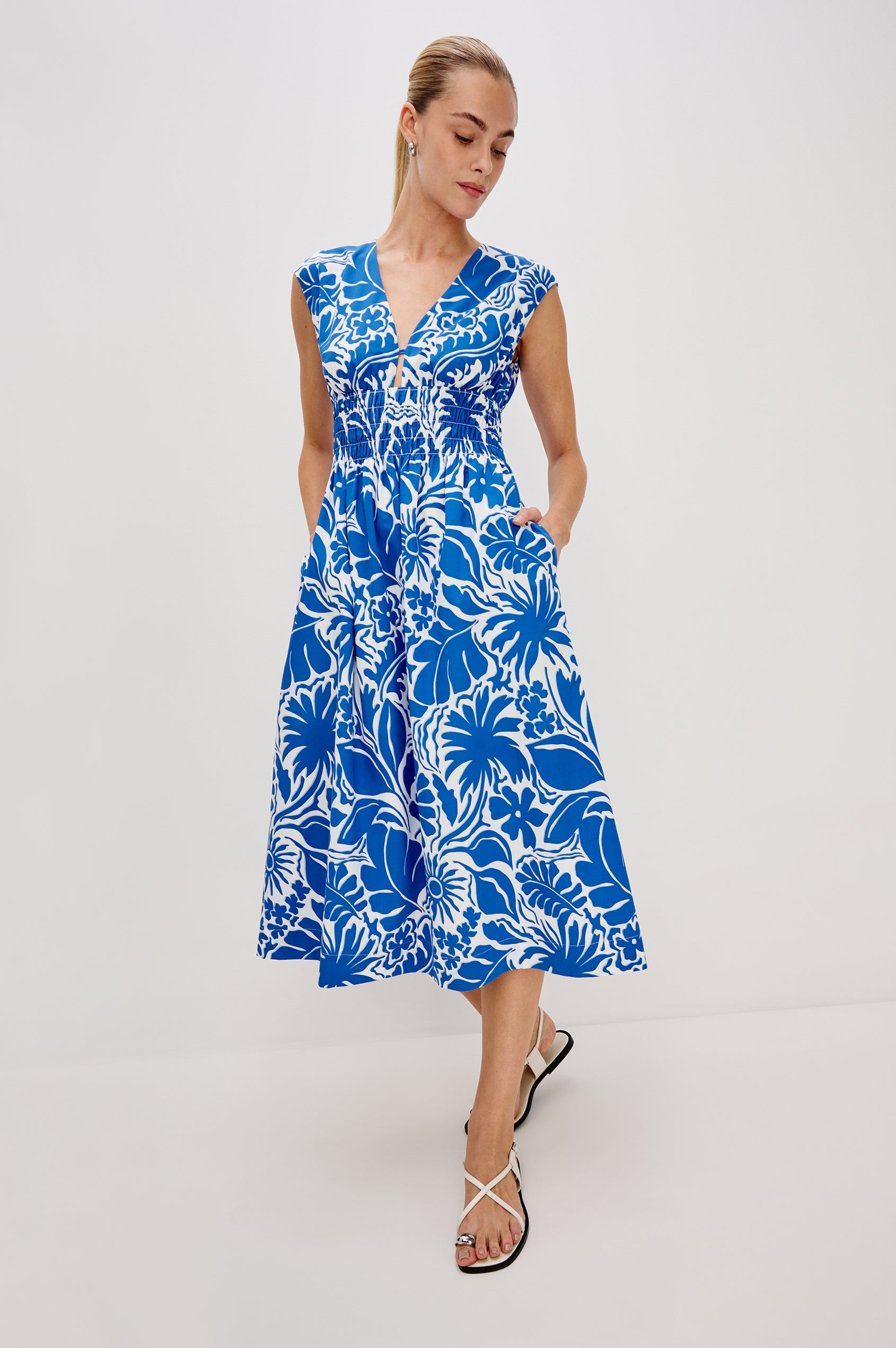 Roxanne A-Line Midi Dress with Smocked Waist, V-Neck, Cap Sleeve and Side Pockets in Blue Riviera Colorway. Full Body Front View Shown on Model.