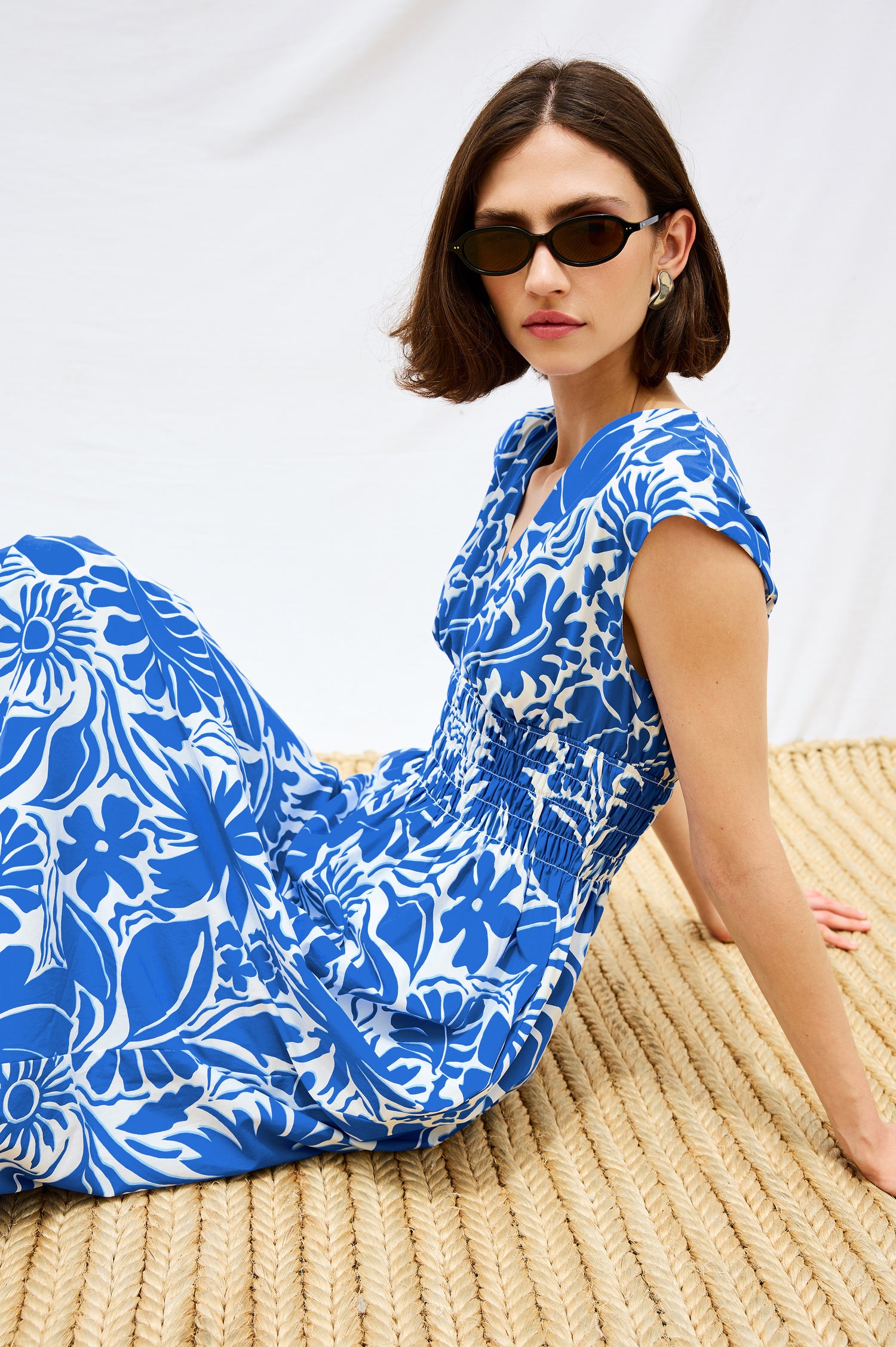 Roxanne A-Line Midi Dress with Smocked Waist, V-Neck, Cap Sleeve and Side Pockets in Blue Riviera Colorway. Stylized Side Detail View Shown on Model.